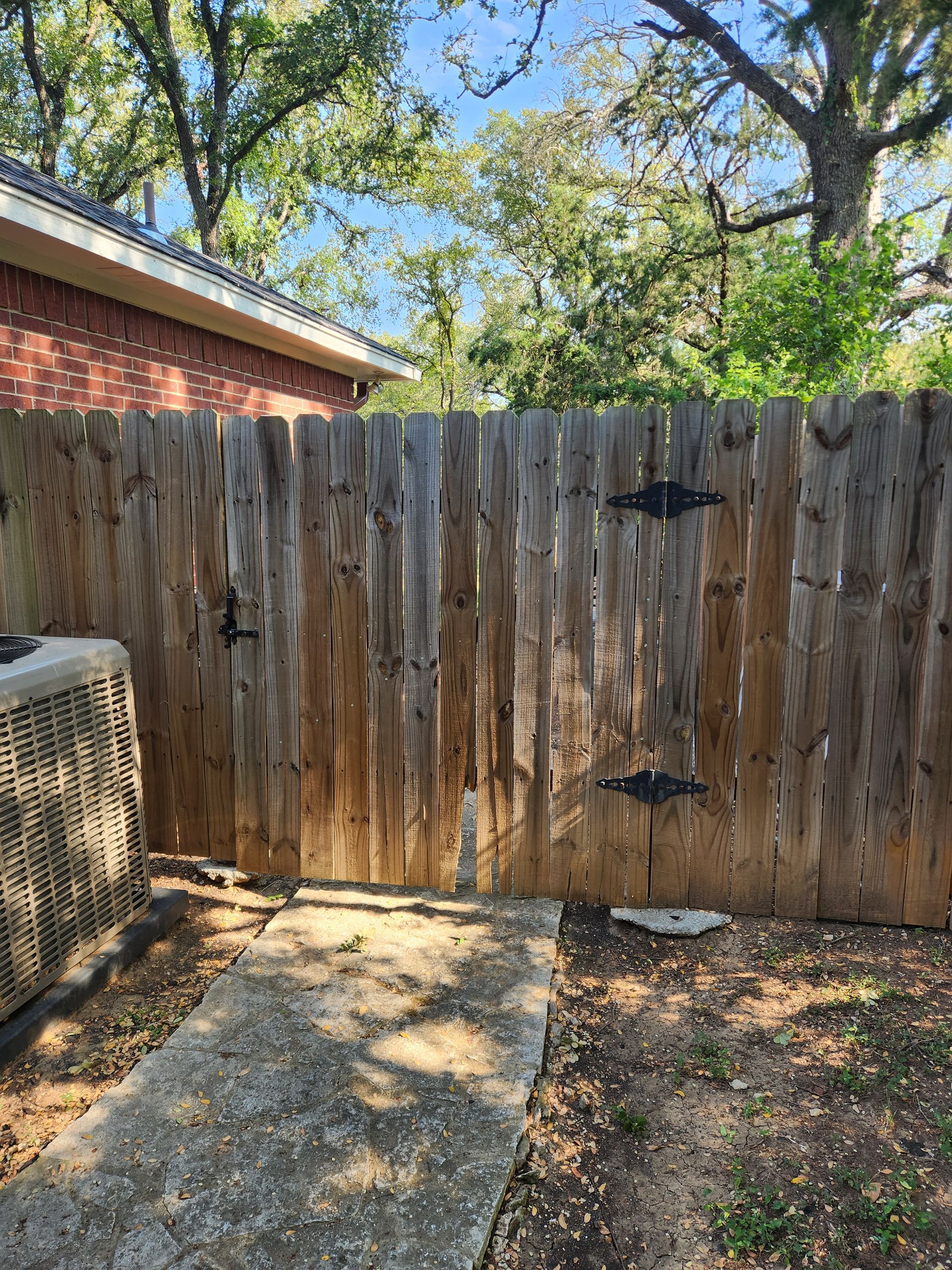 A wooden fence with a gate in the backyard of a house.
