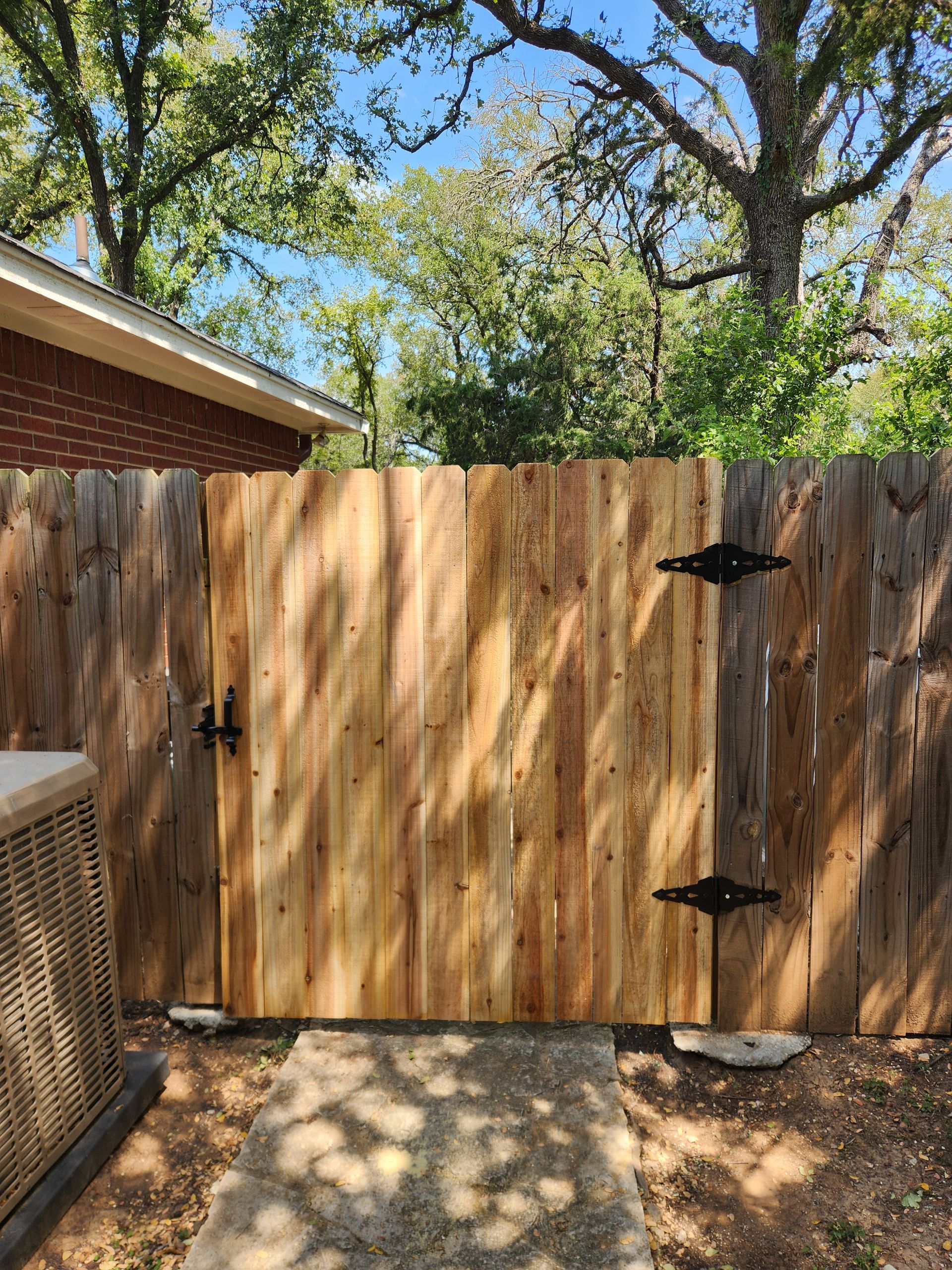A wooden fence with a gate in the backyard of a house.