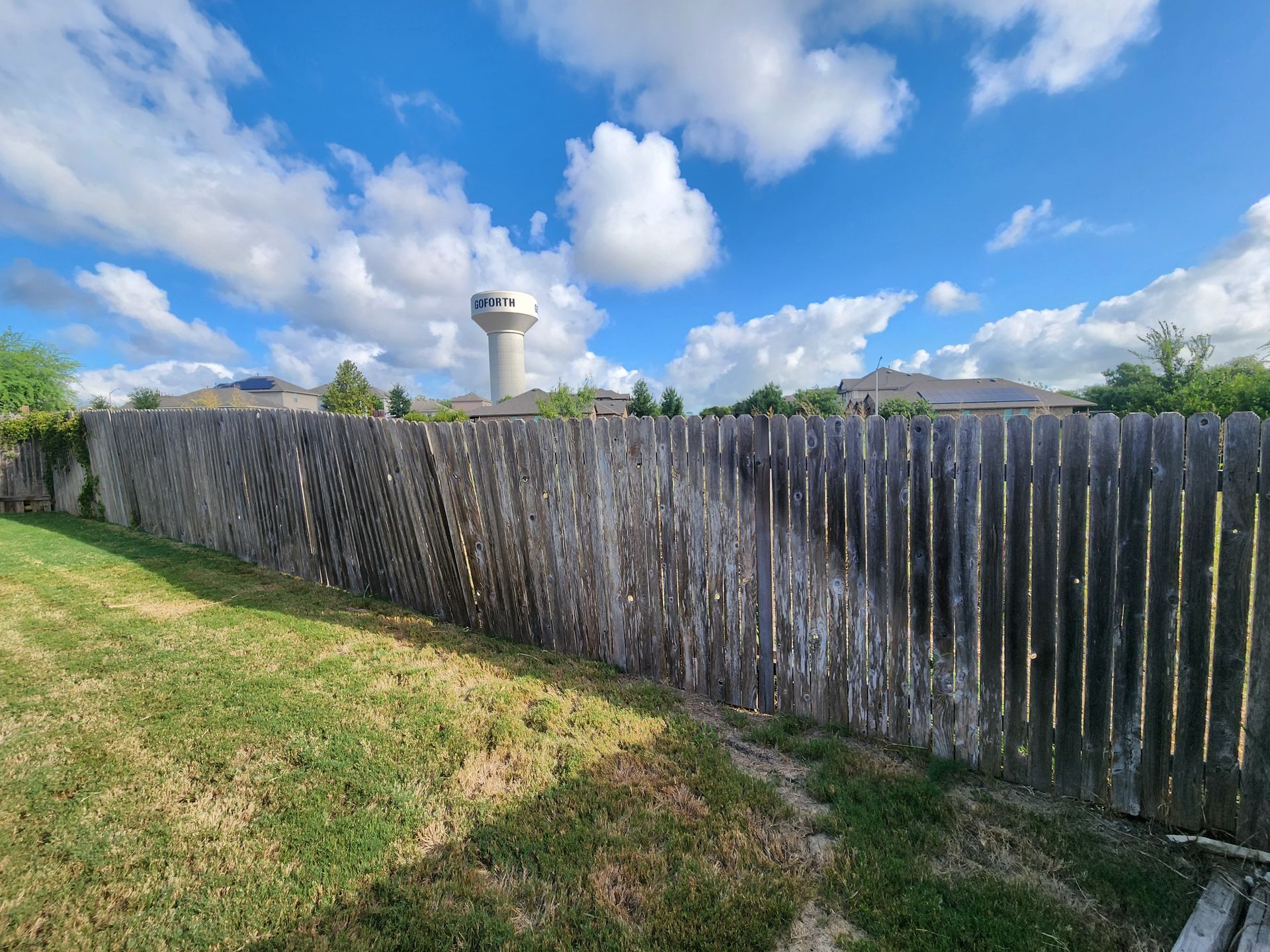 A wooden fence with a water tower in the background.
