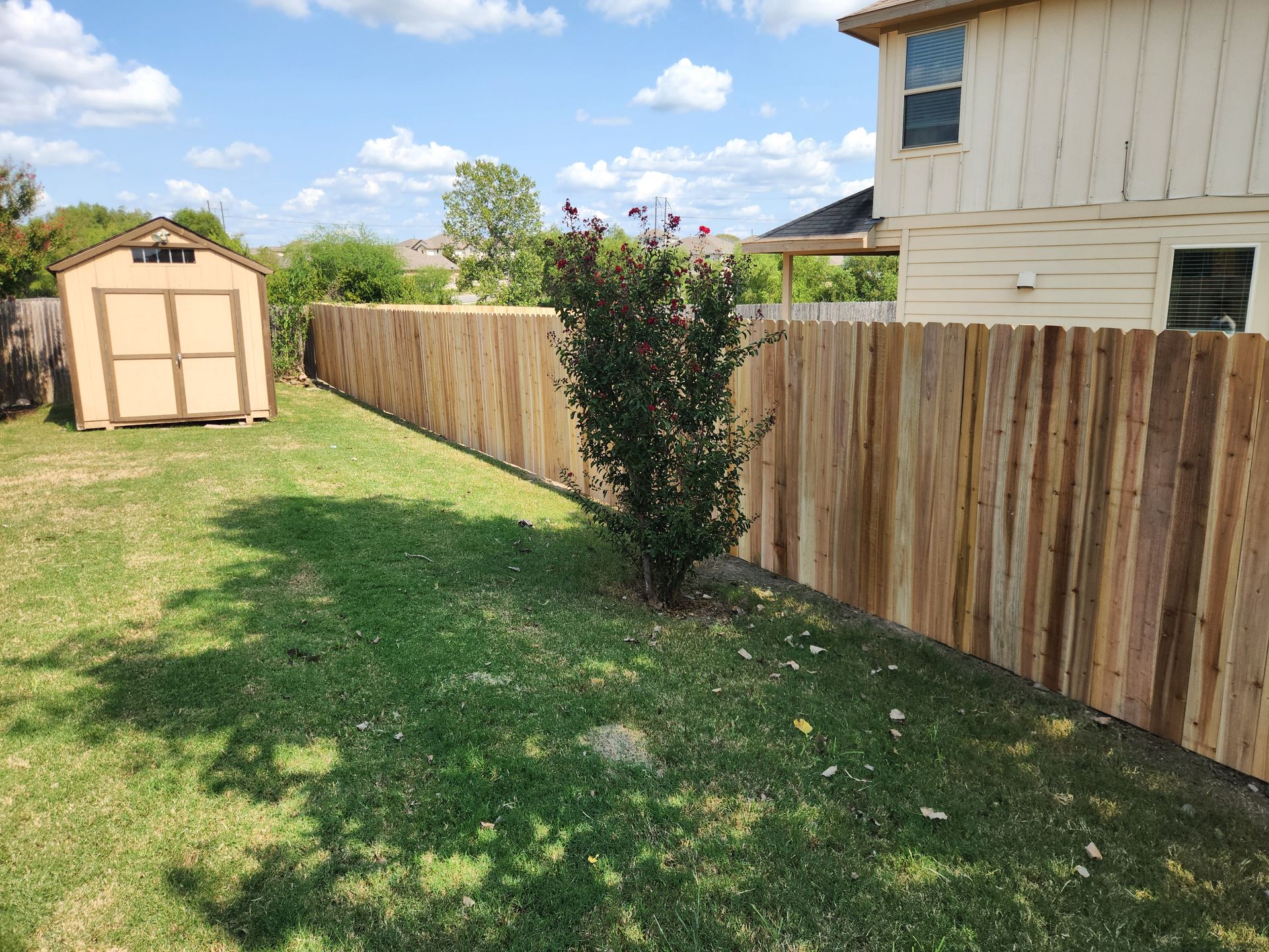 A wooden fence is in the backyard of a house.