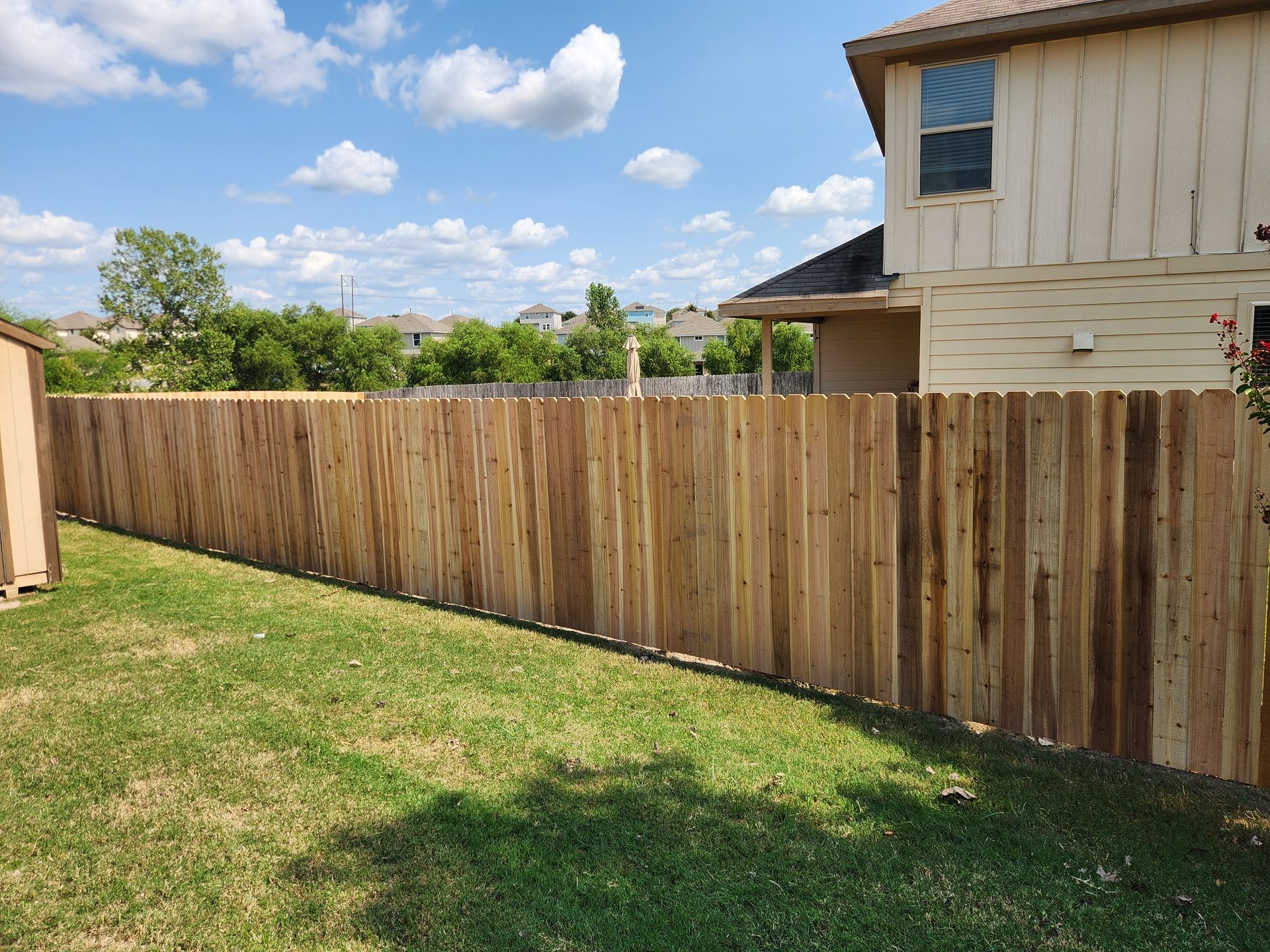 A wooden fence is in the backyard of a house.