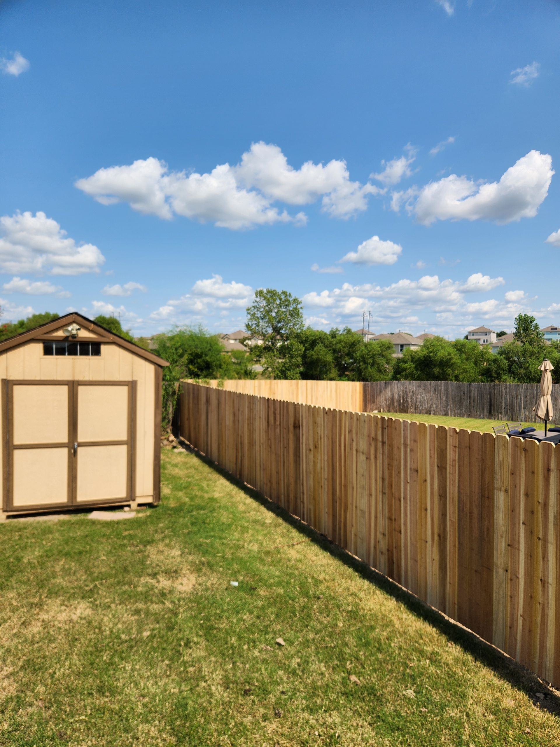 A shed is sitting next to a wooden fence in a backyard.