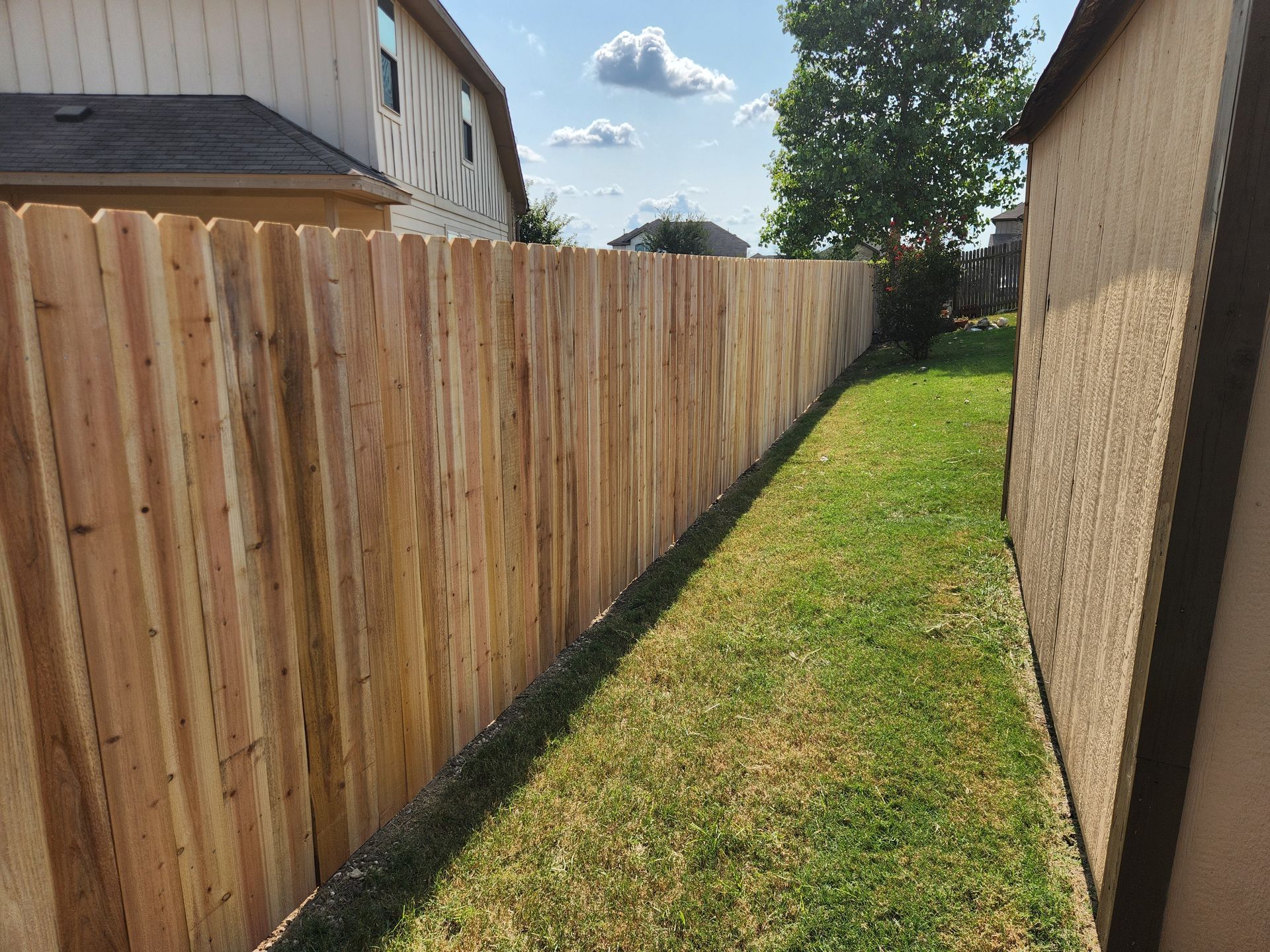 A wooden fence is in the backyard of a house.