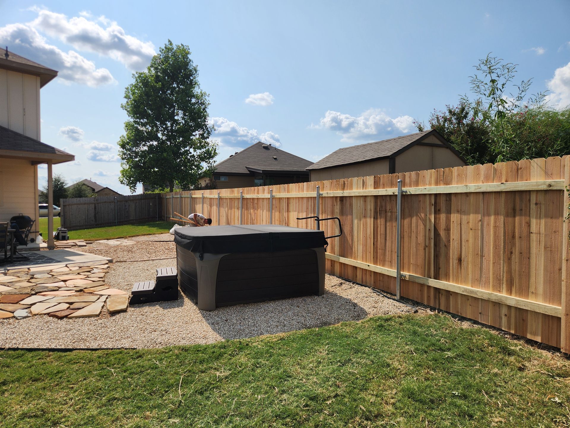 A hot tub is sitting in the backyard next to a wooden fence.