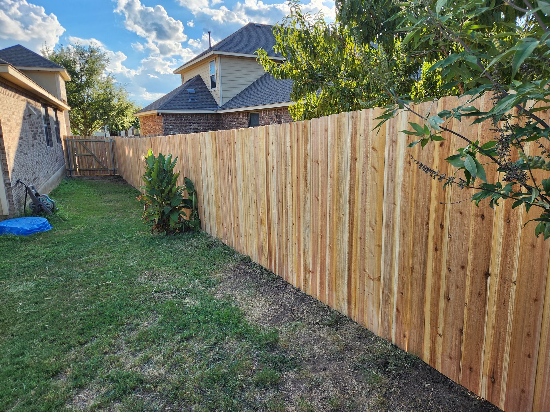 A wooden fence is in the backyard of a house.