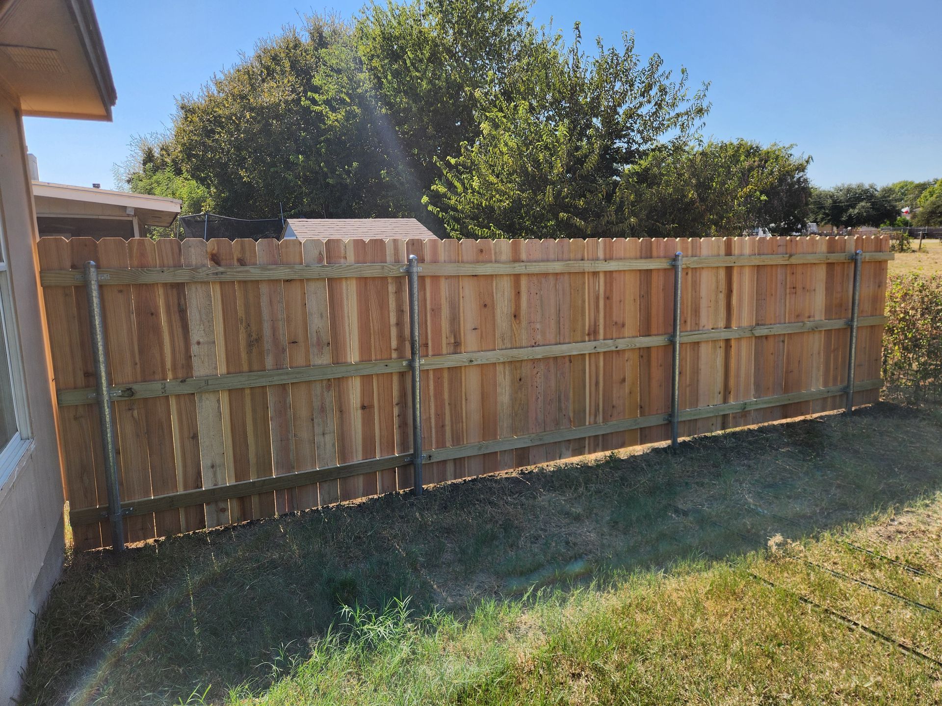 A wooden fence is in the backyard of a house.