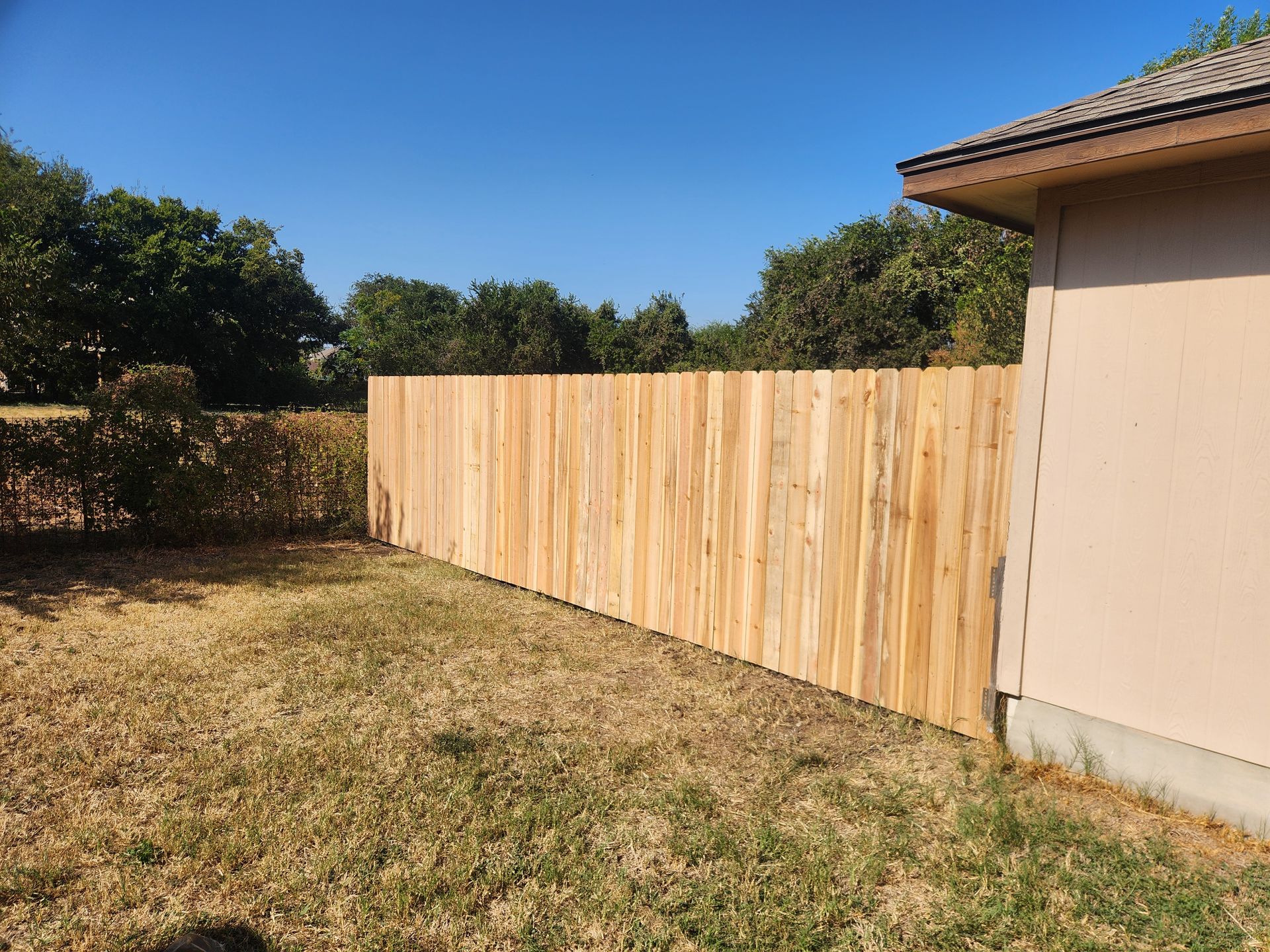 A wooden fence is in the backyard of a house.