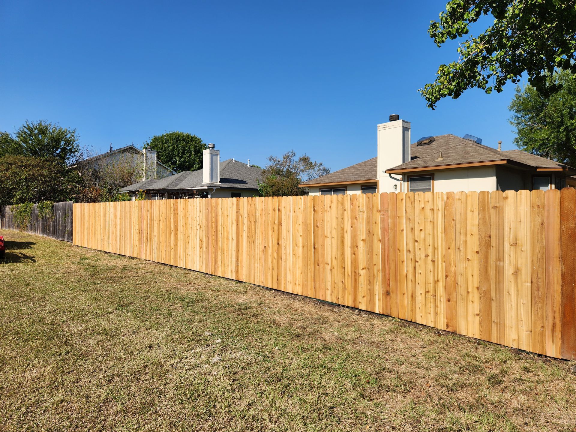 A wooden fence is in the backyard of a house.