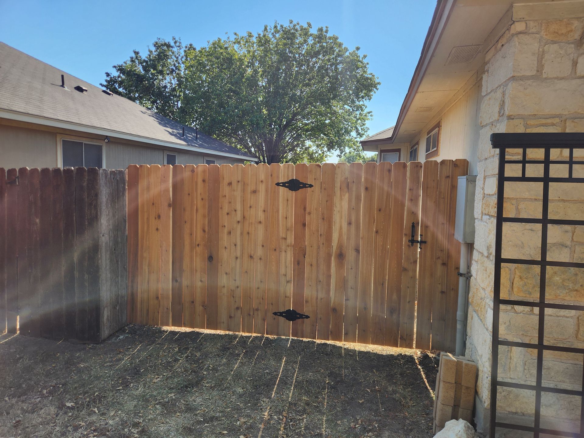A wooden fence with a gate in the backyard of a house.