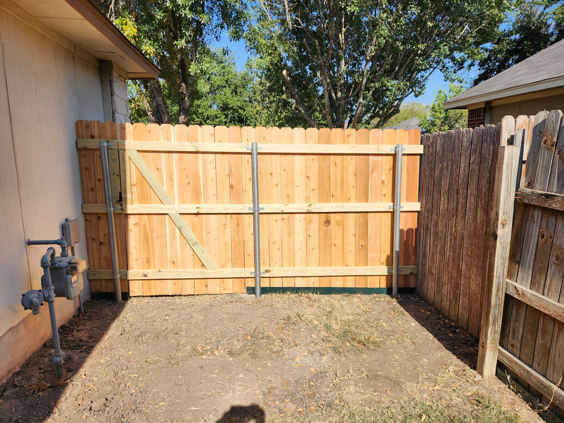 A wooden fence with a gate in the backyard of a house.