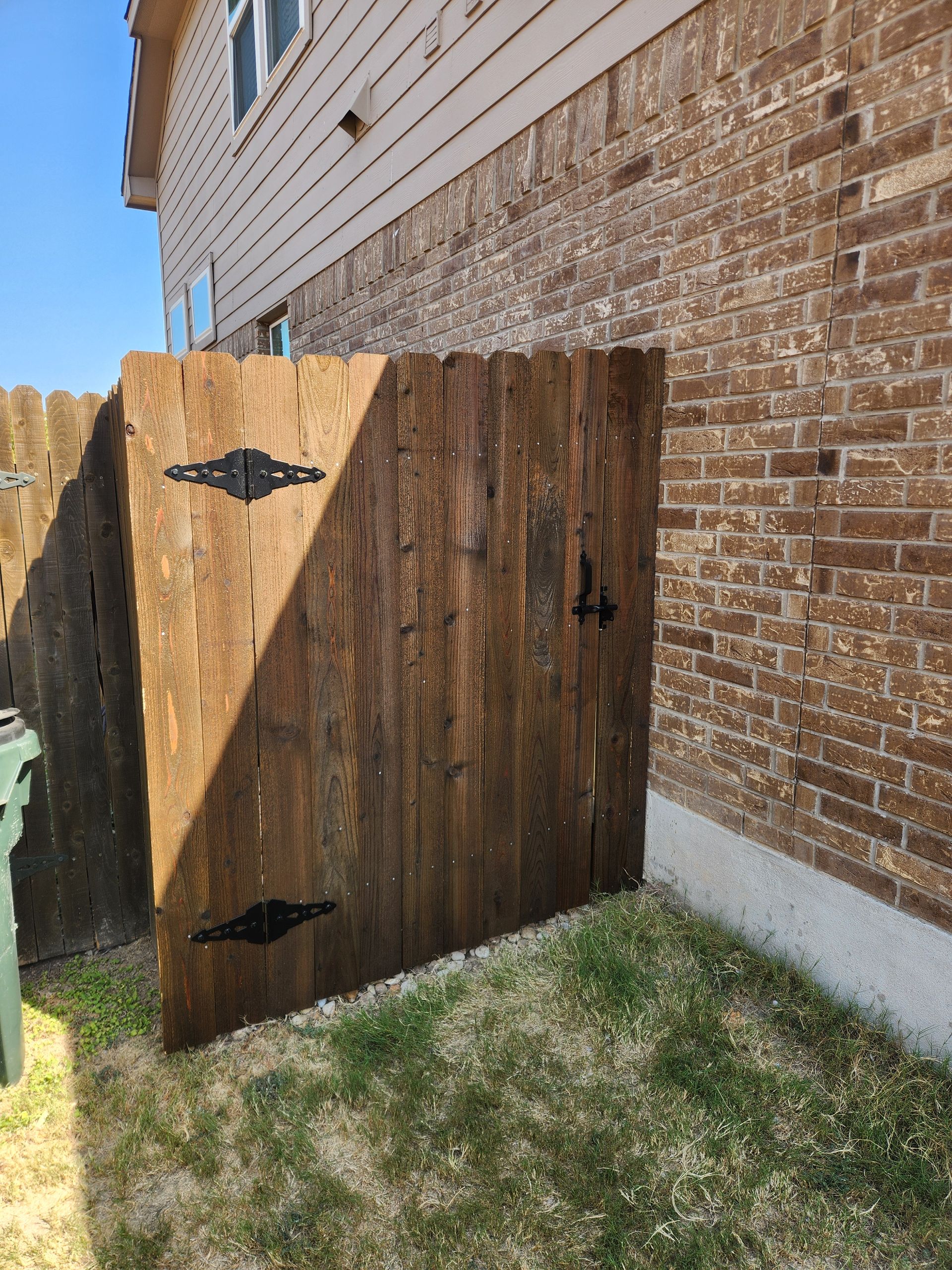 A wooden fence is sitting in front of a brick building.