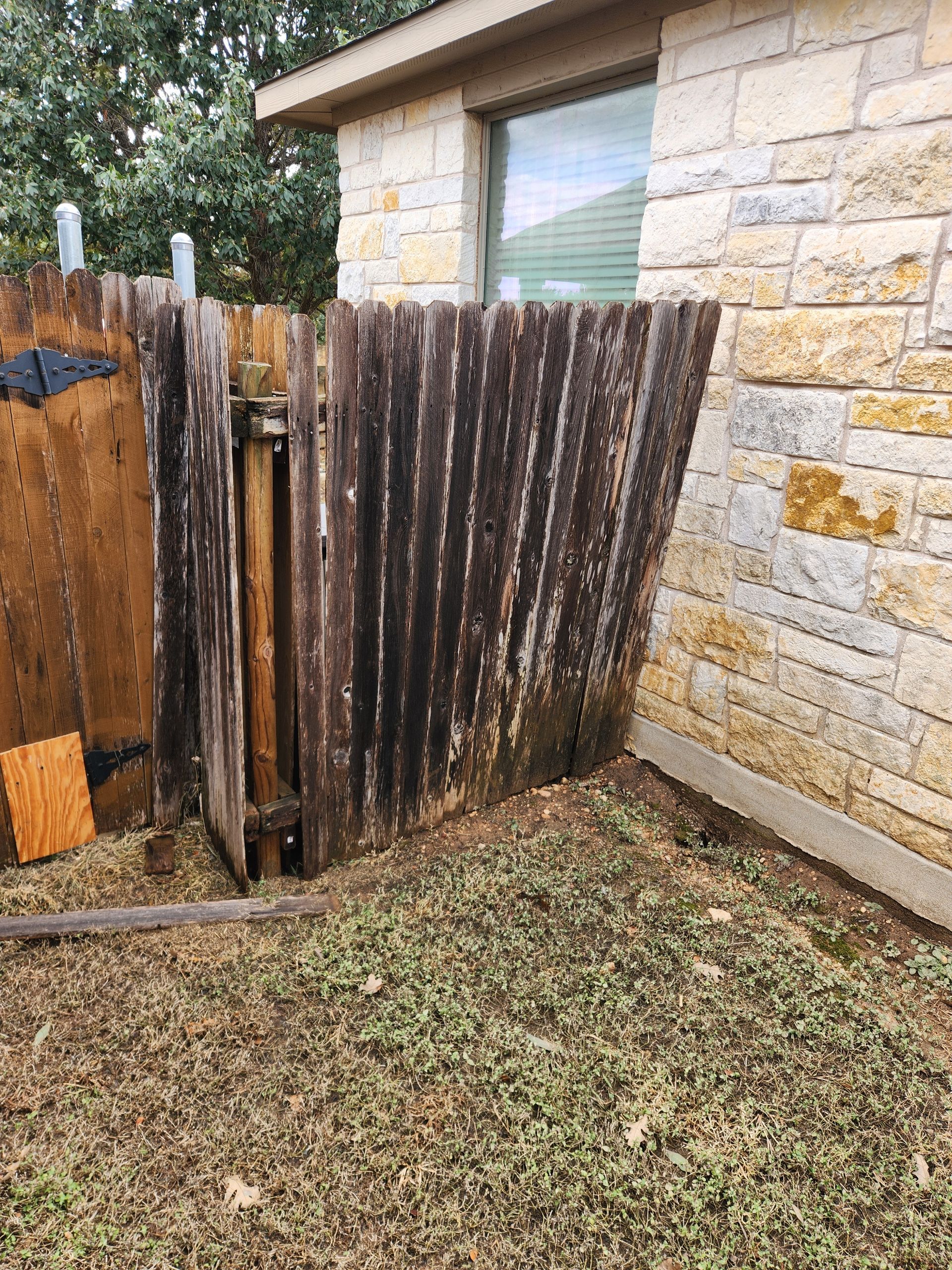 A wooden fence is sitting in front of a brick house.