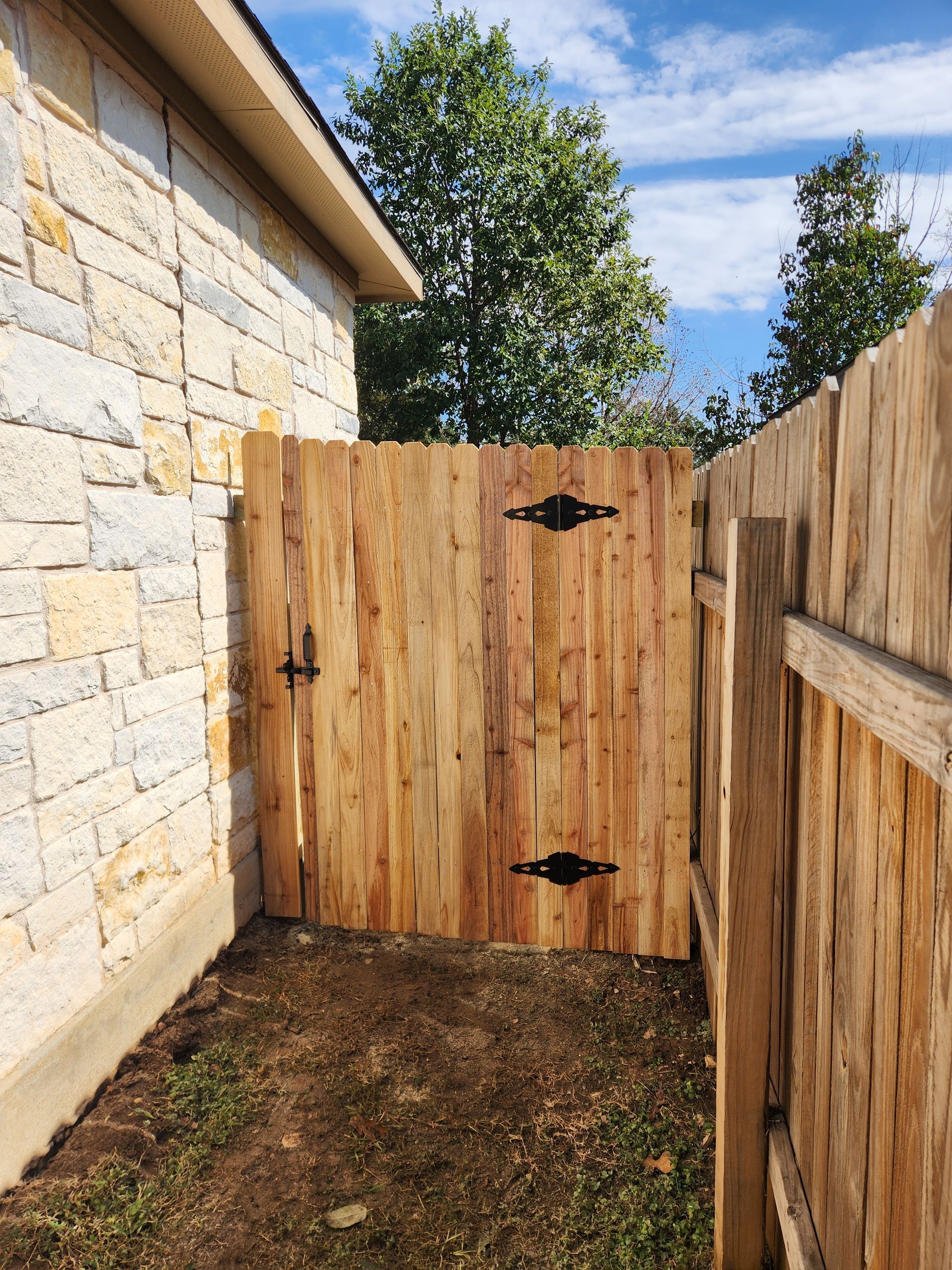 A wooden fence with a gate in the backyard of a house.