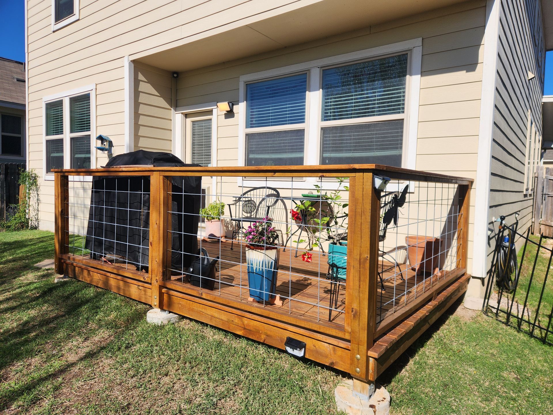 A wooden deck with a fence around it is in front of a house.
