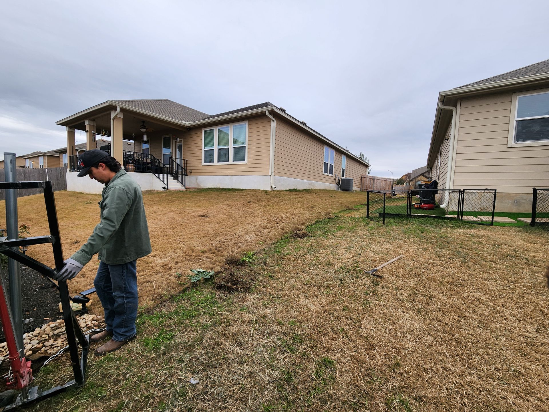 A man is working on a fence in front of a house.