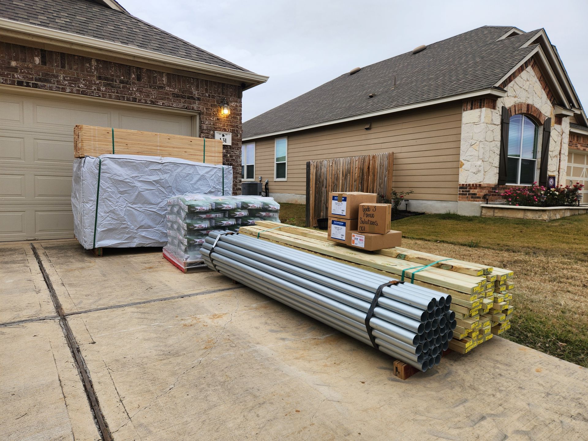 A pile of pipes and wood is sitting in front of a house.