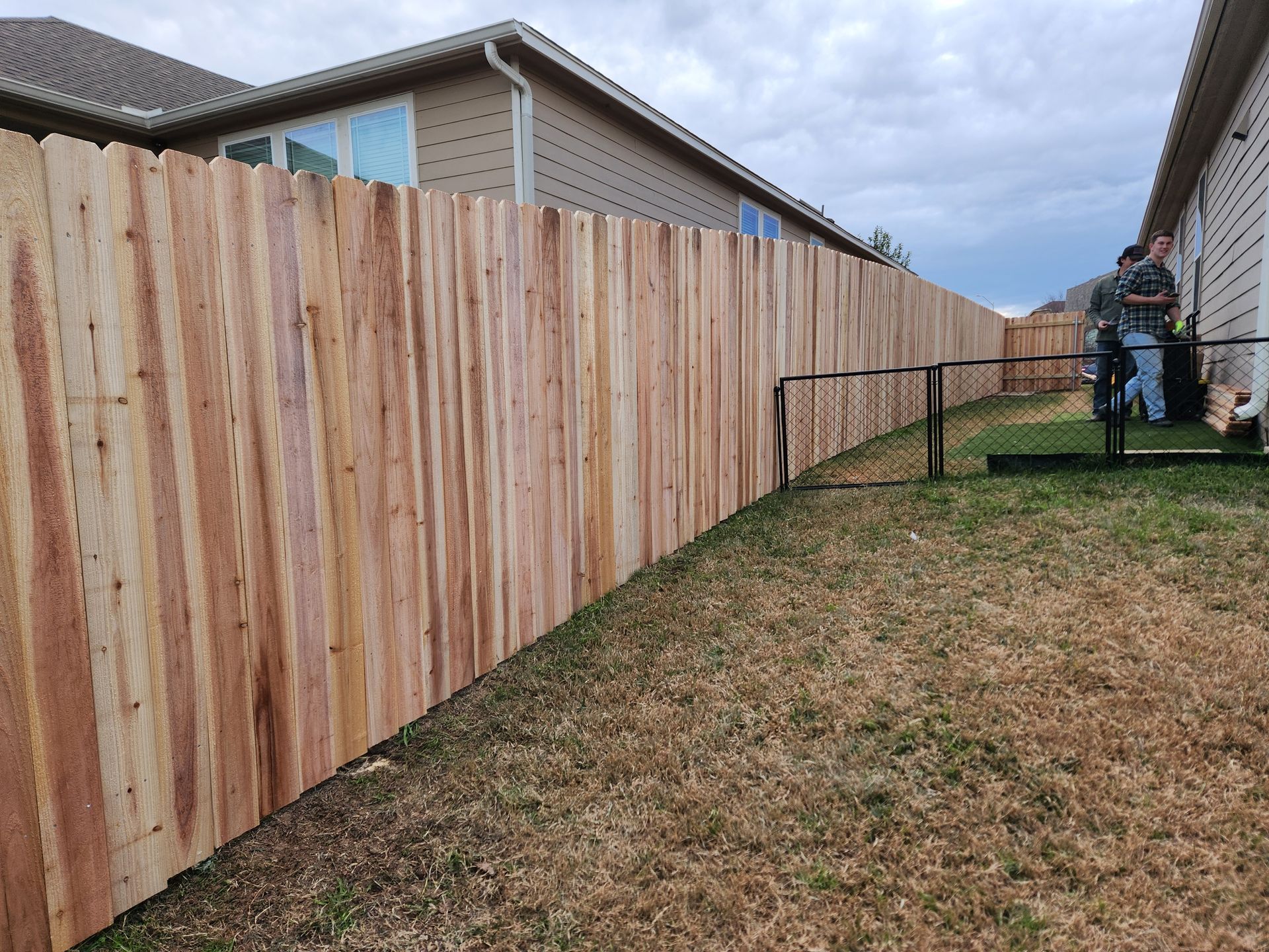 A wooden fence is in the backyard of a house.