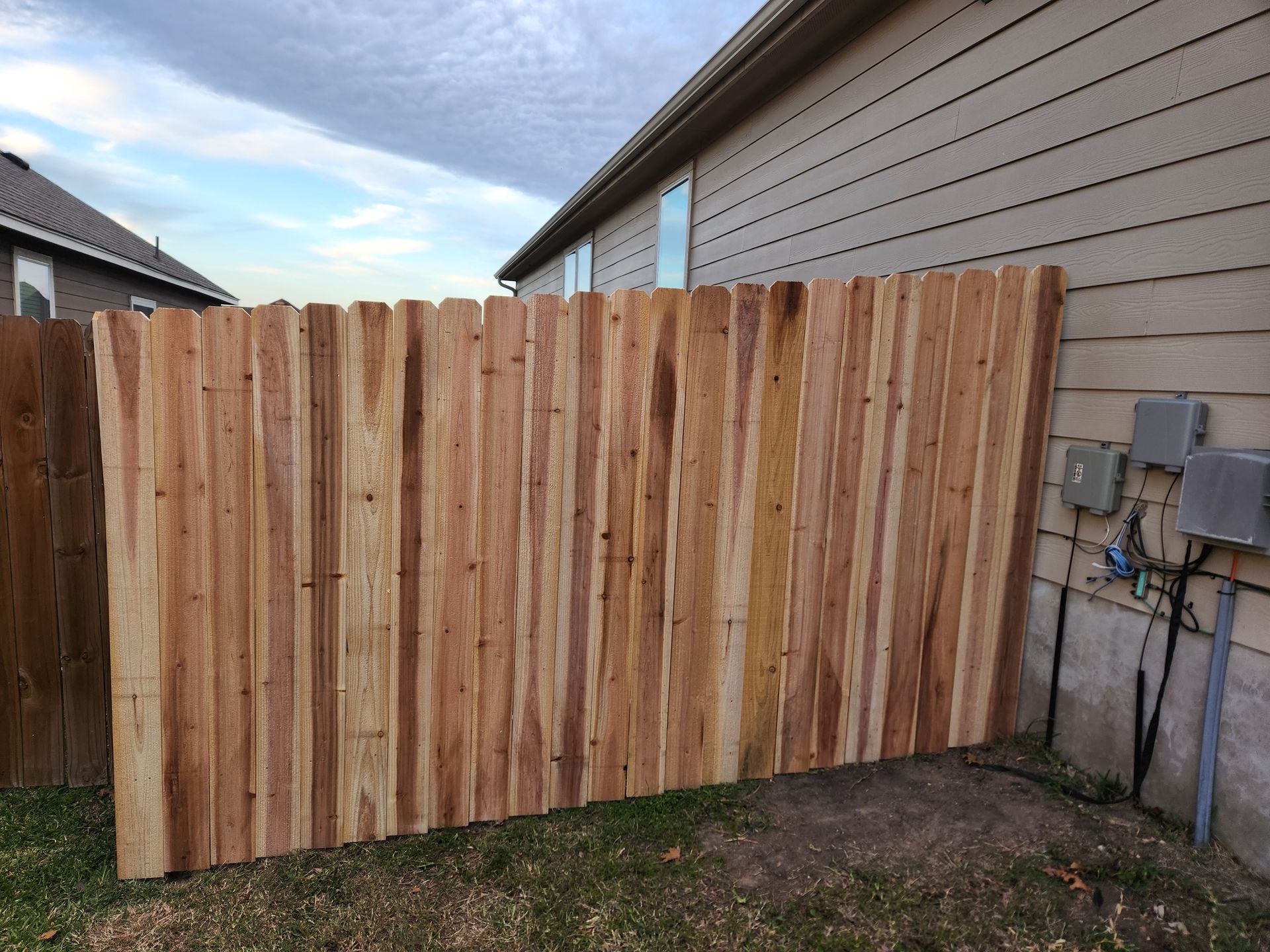 A wooden fence is in the backyard of a house.