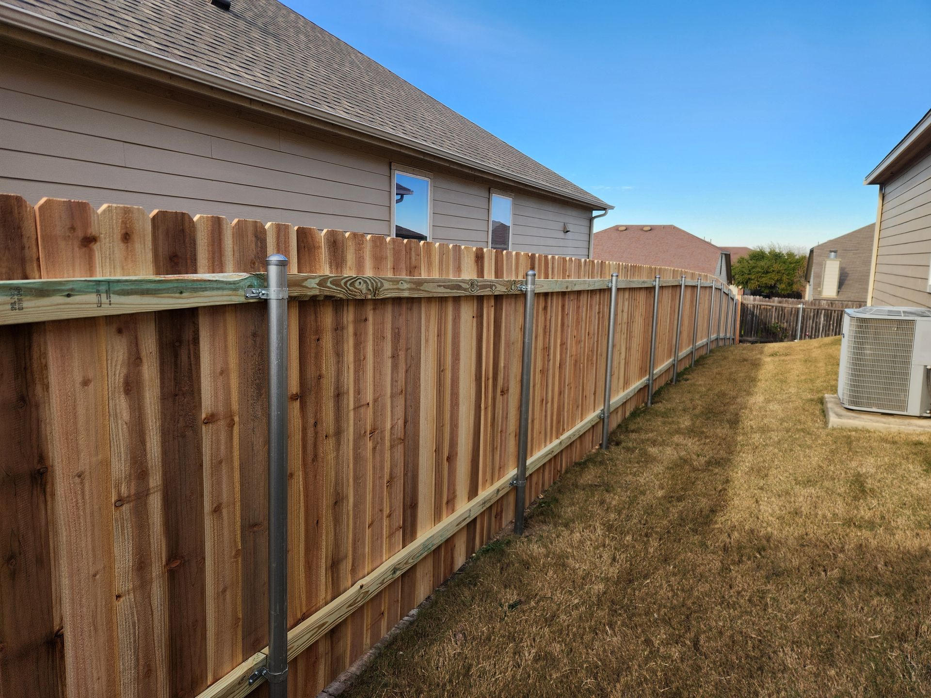 A wooden fence is in the backyard of a house.