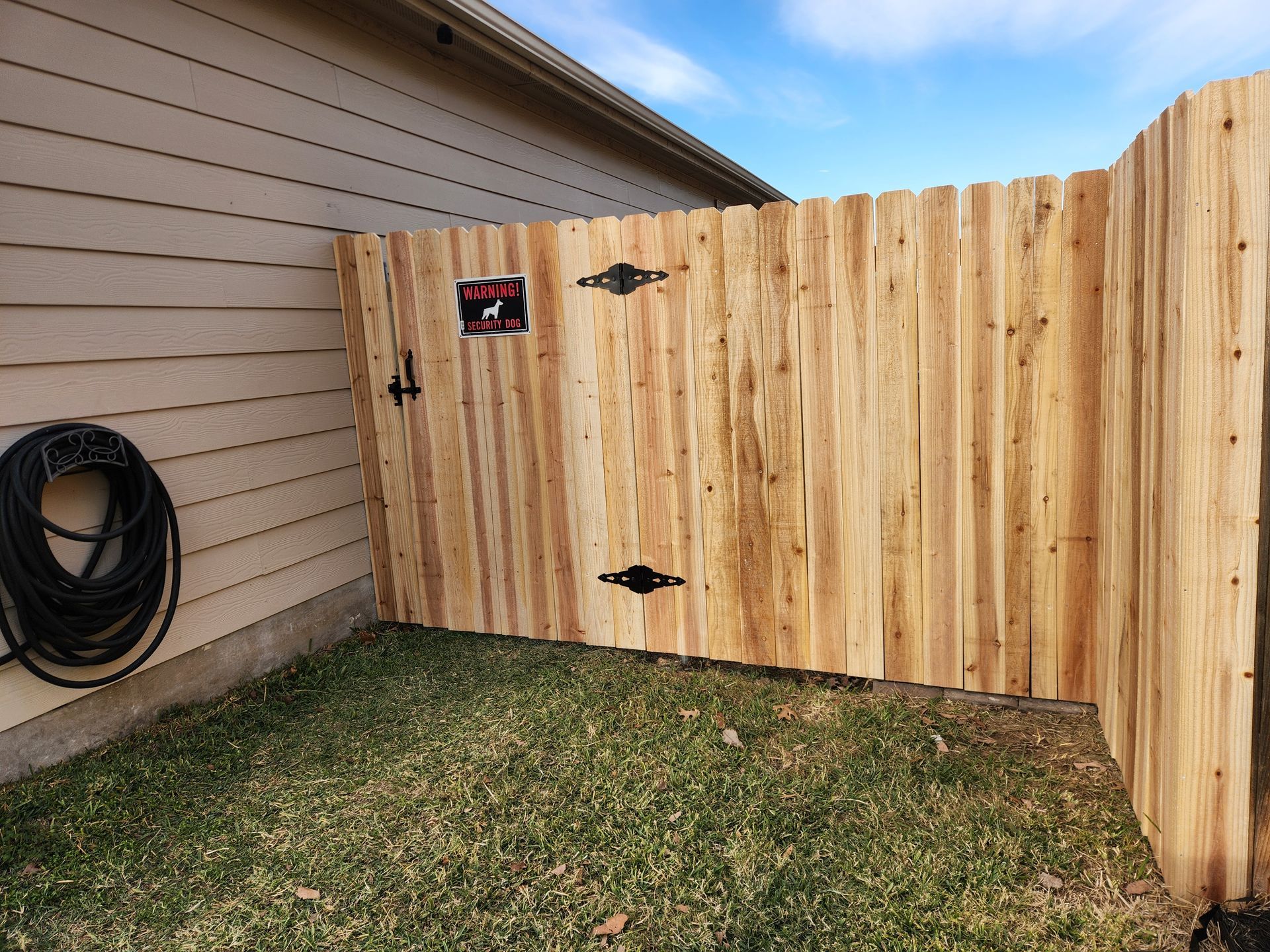 A wooden fence with a gate in the backyard of a house.