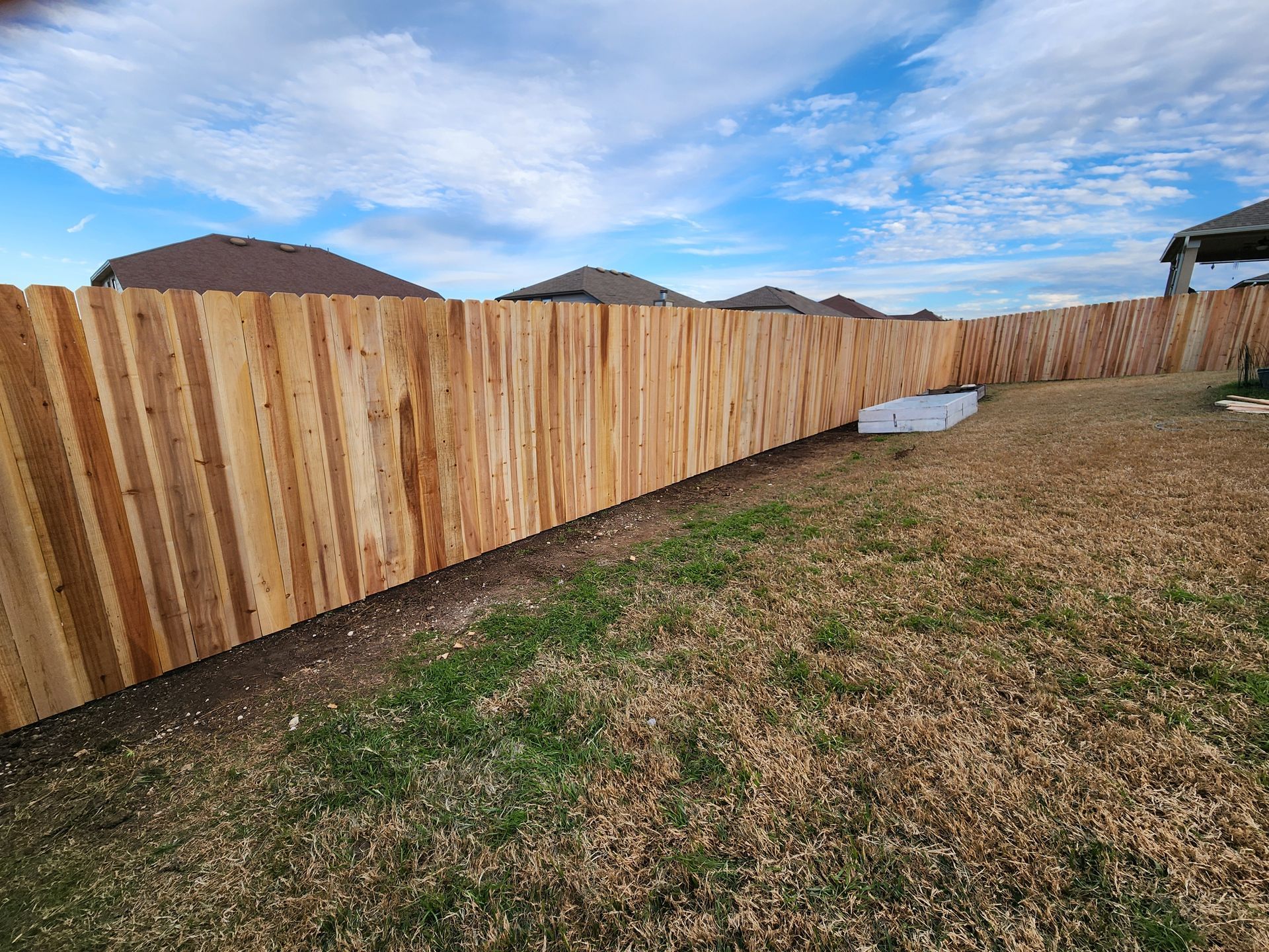 A wooden fence is in the backyard of a house.