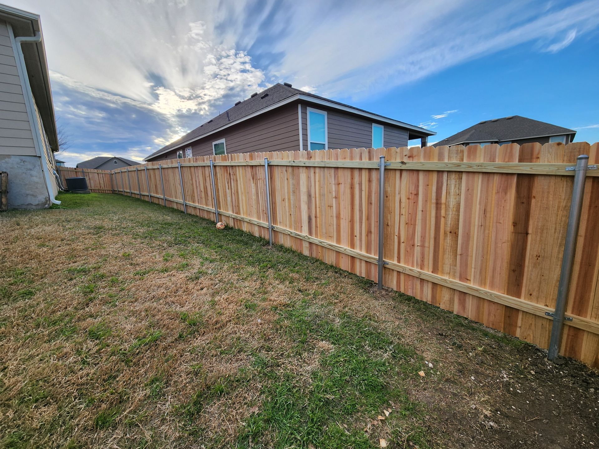 A wooden fence is in the backyard of a house.
