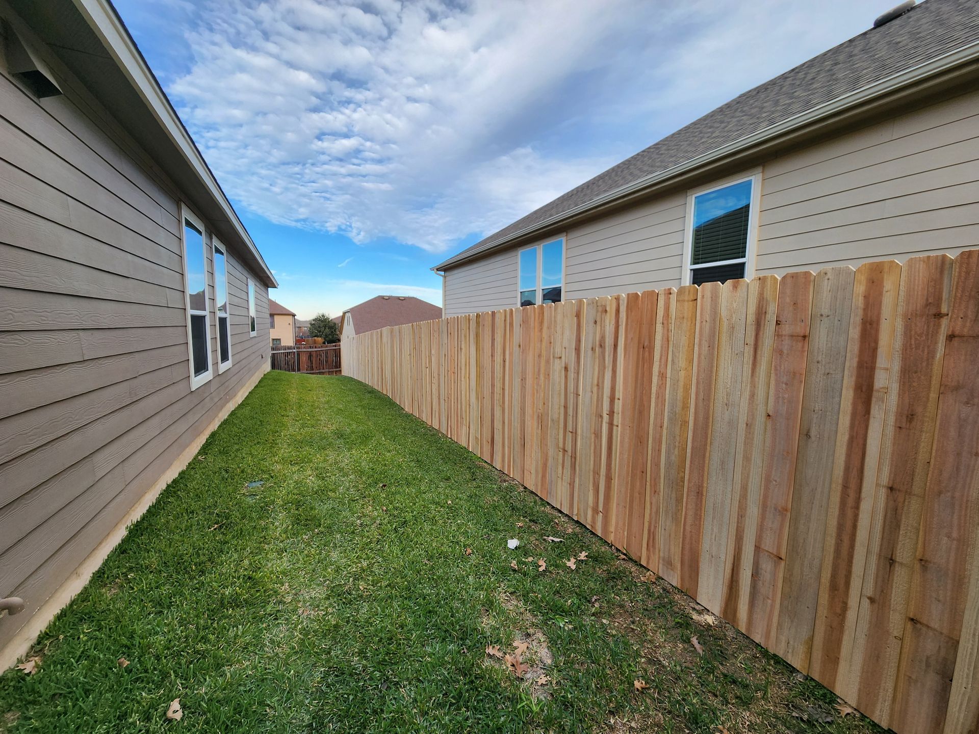A wooden fence is in the backyard of a house.