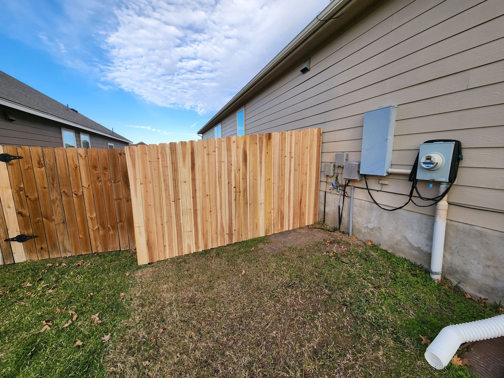A wooden fence is in the backyard of a house.