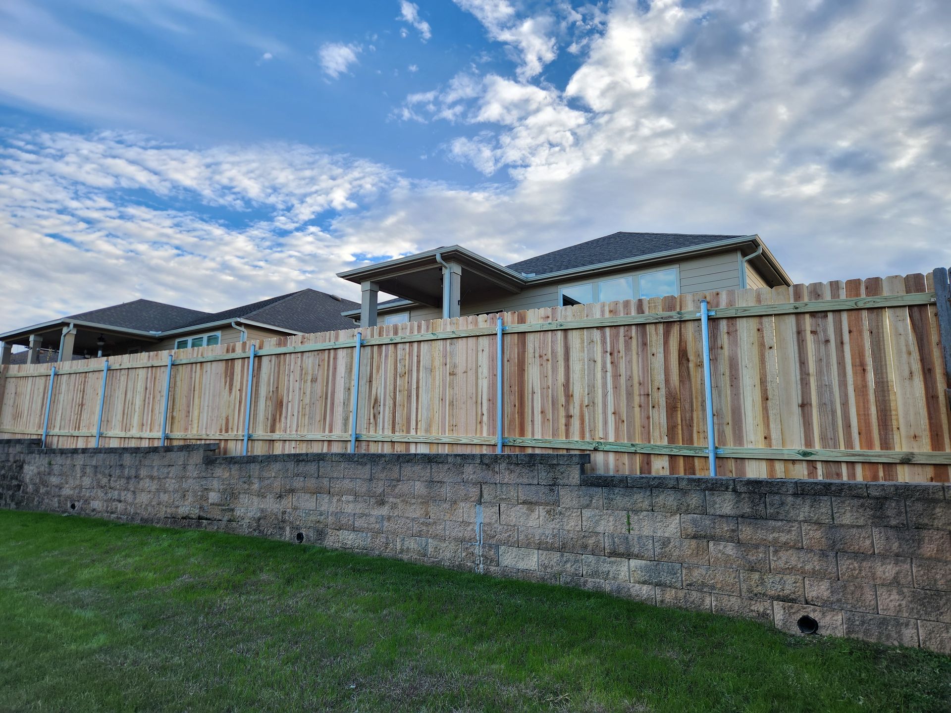 A wooden fence surrounds a brick wall in front of a house.