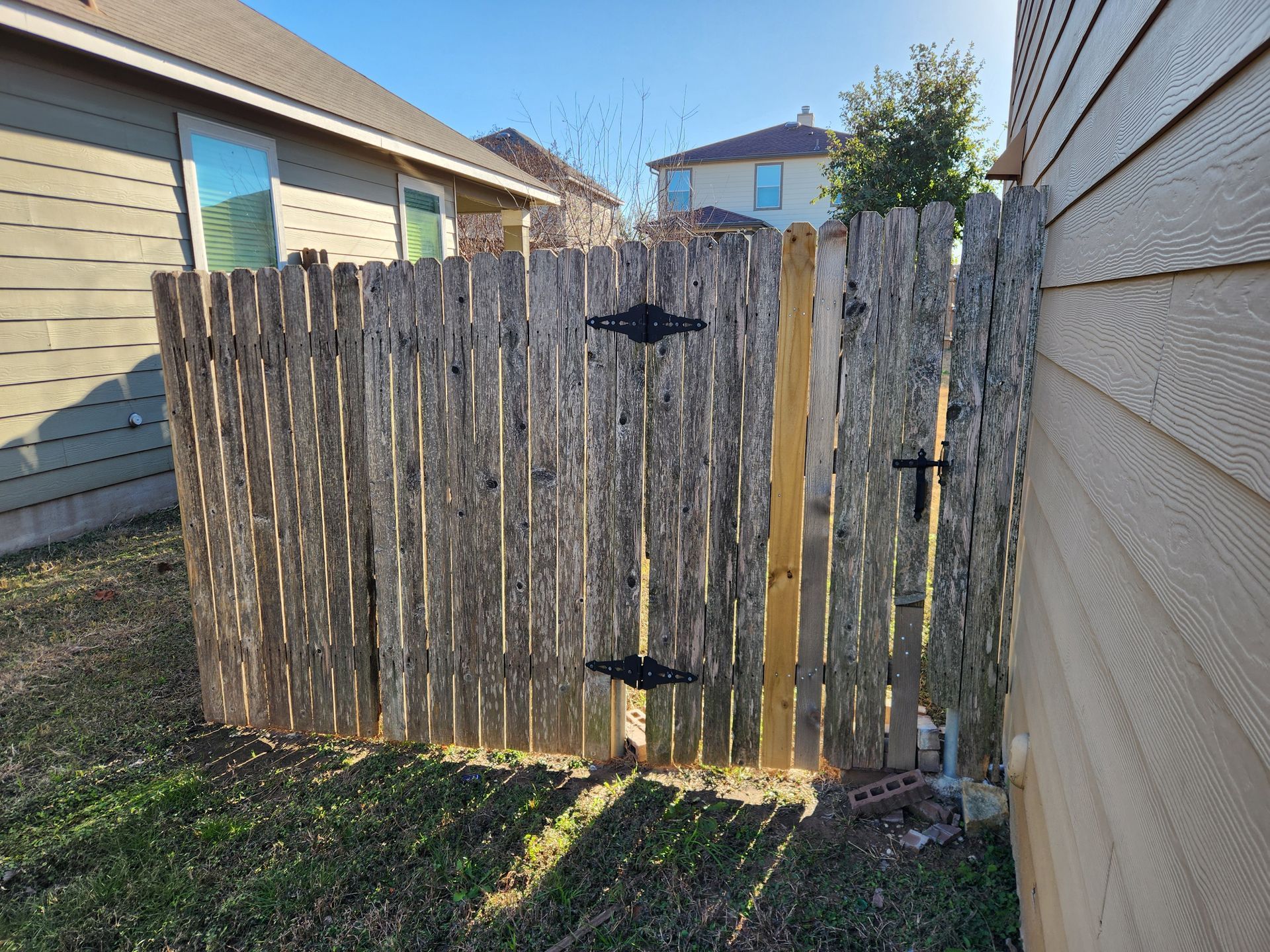 A wooden fence with a gate in the backyard of a house.