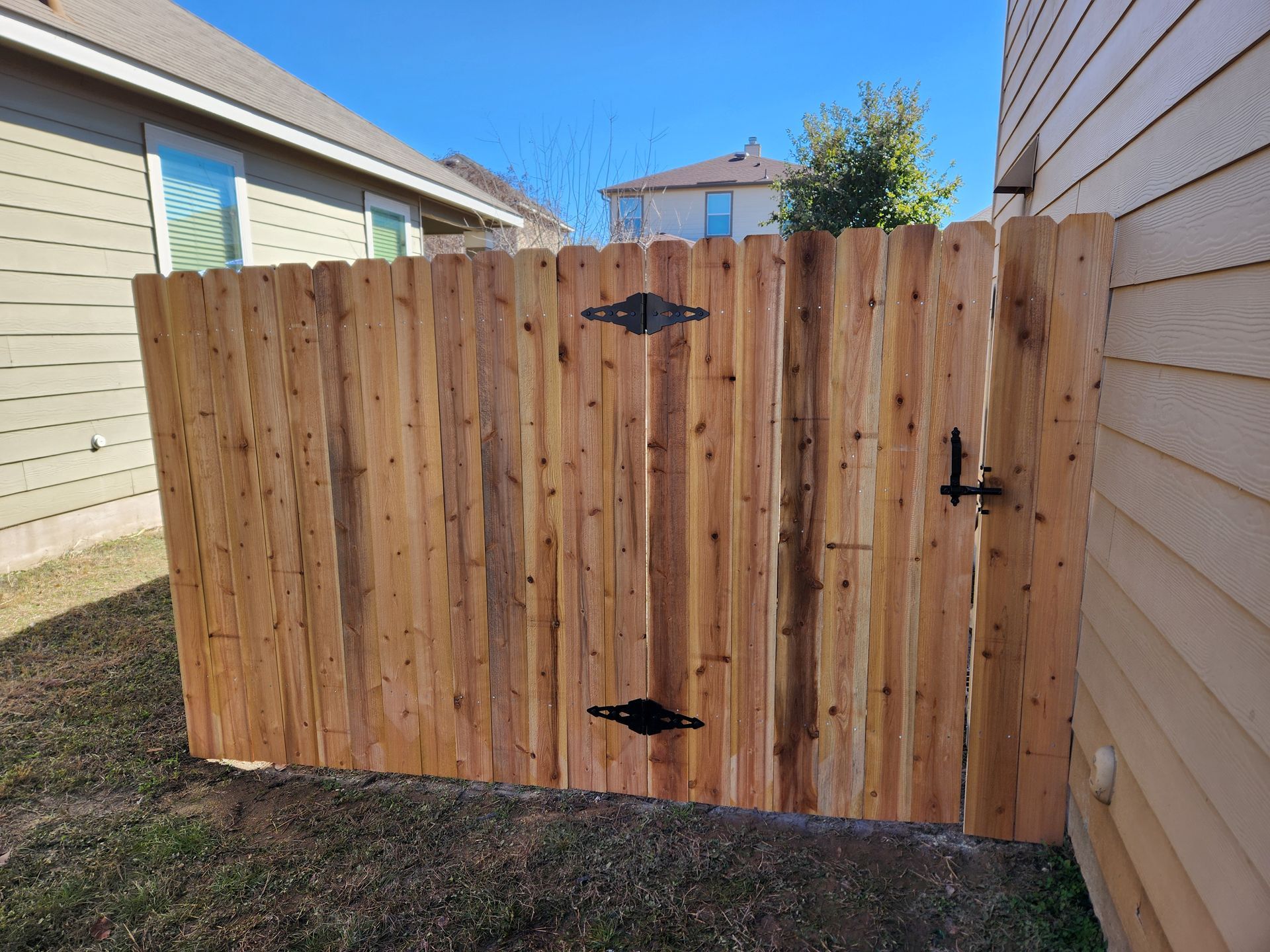 A wooden fence with a gate in the backyard of a house.