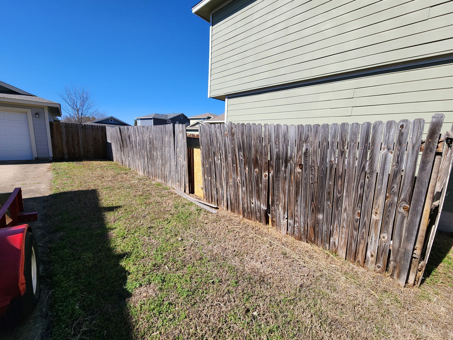 A wooden fence is in the backyard of a house.