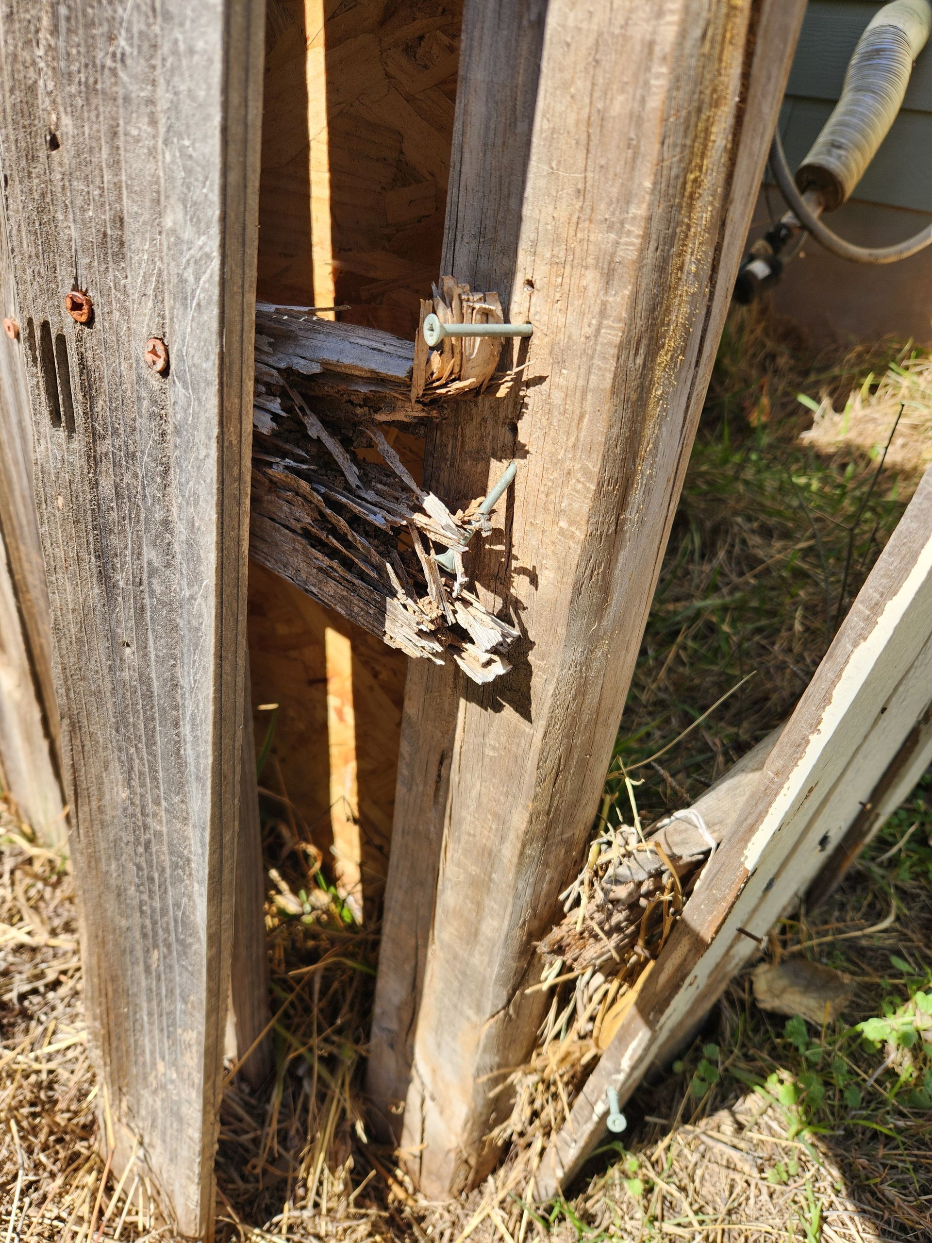 A close up of a wooden fence with a hole in it.