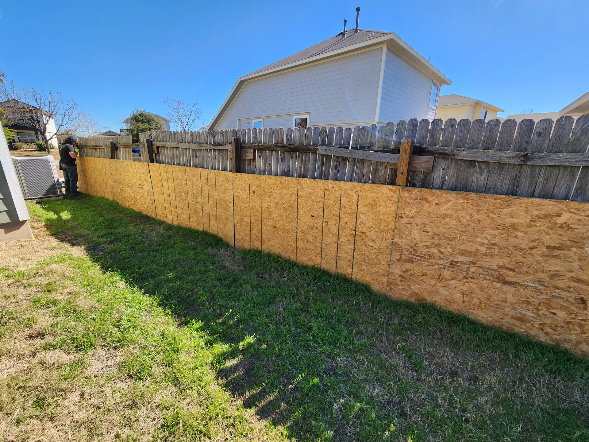 A wooden fence is being built in the backyard of a house.