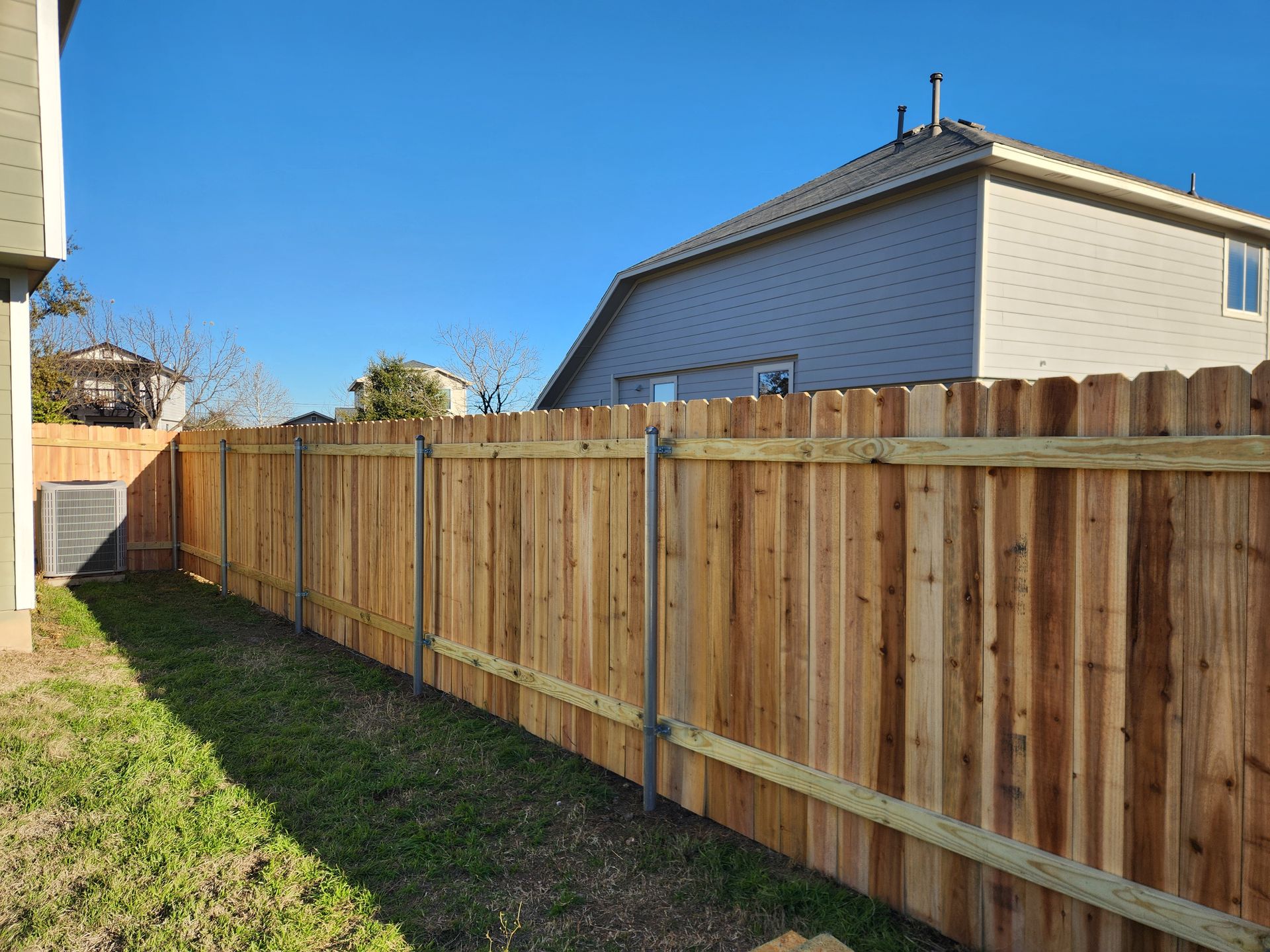 A wooden fence is in the backyard of a house.