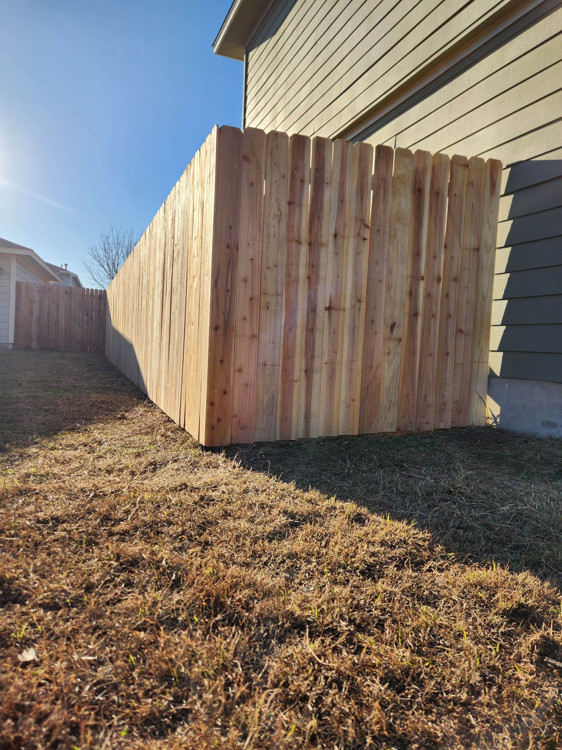 A wooden fence is sitting in the grass in front of a house.