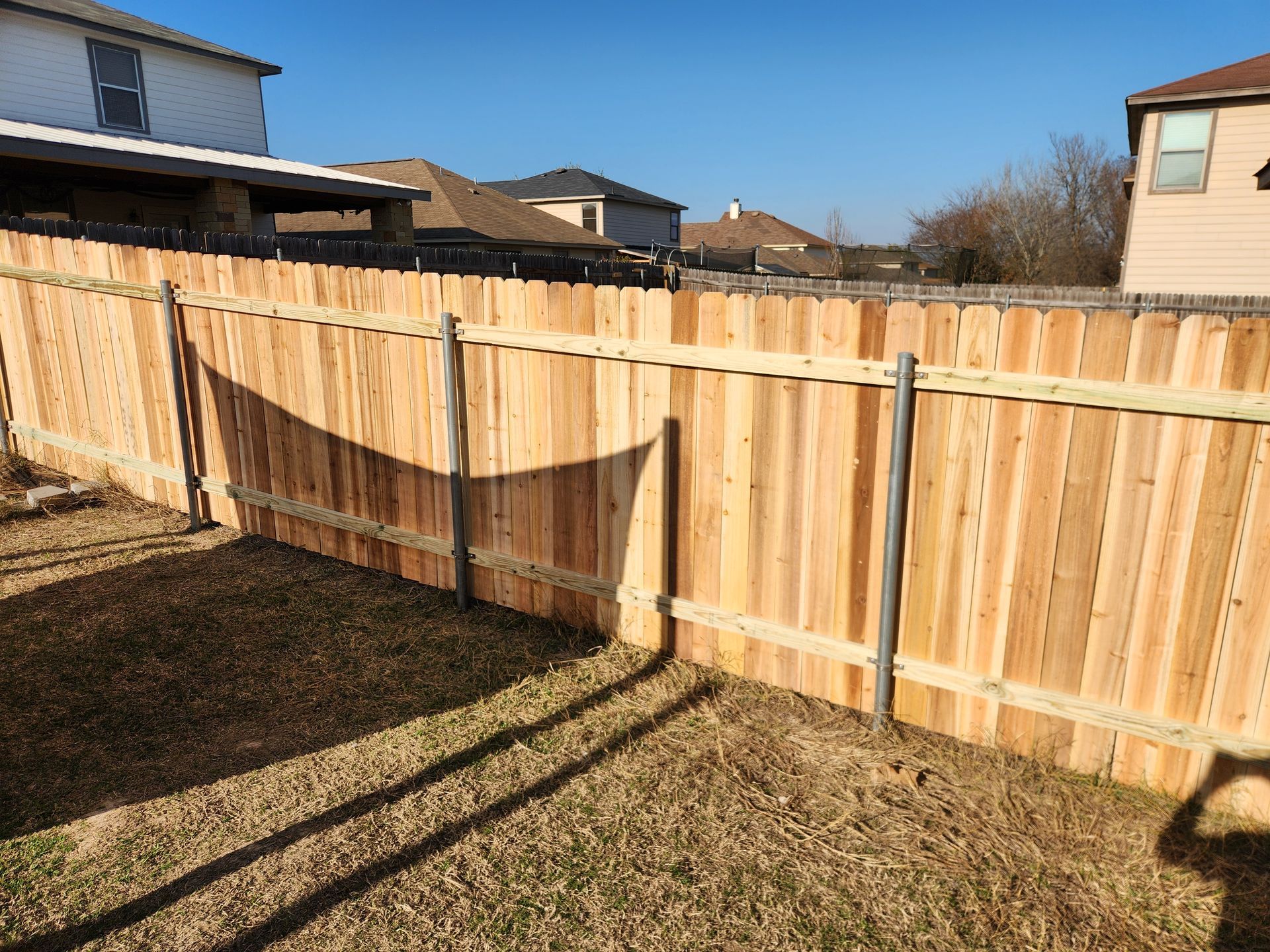 A wooden fence is in the backyard of a house.