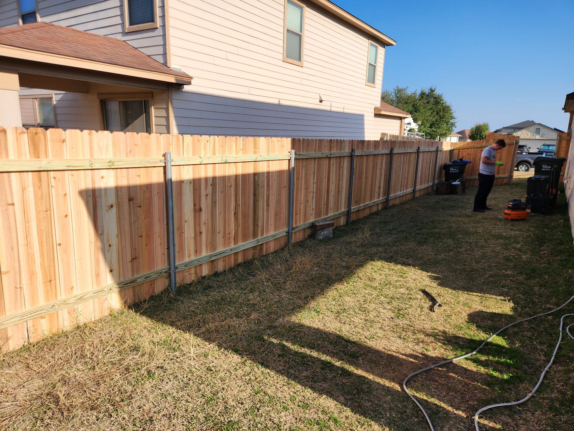 A wooden fence is being built in the backyard of a house.