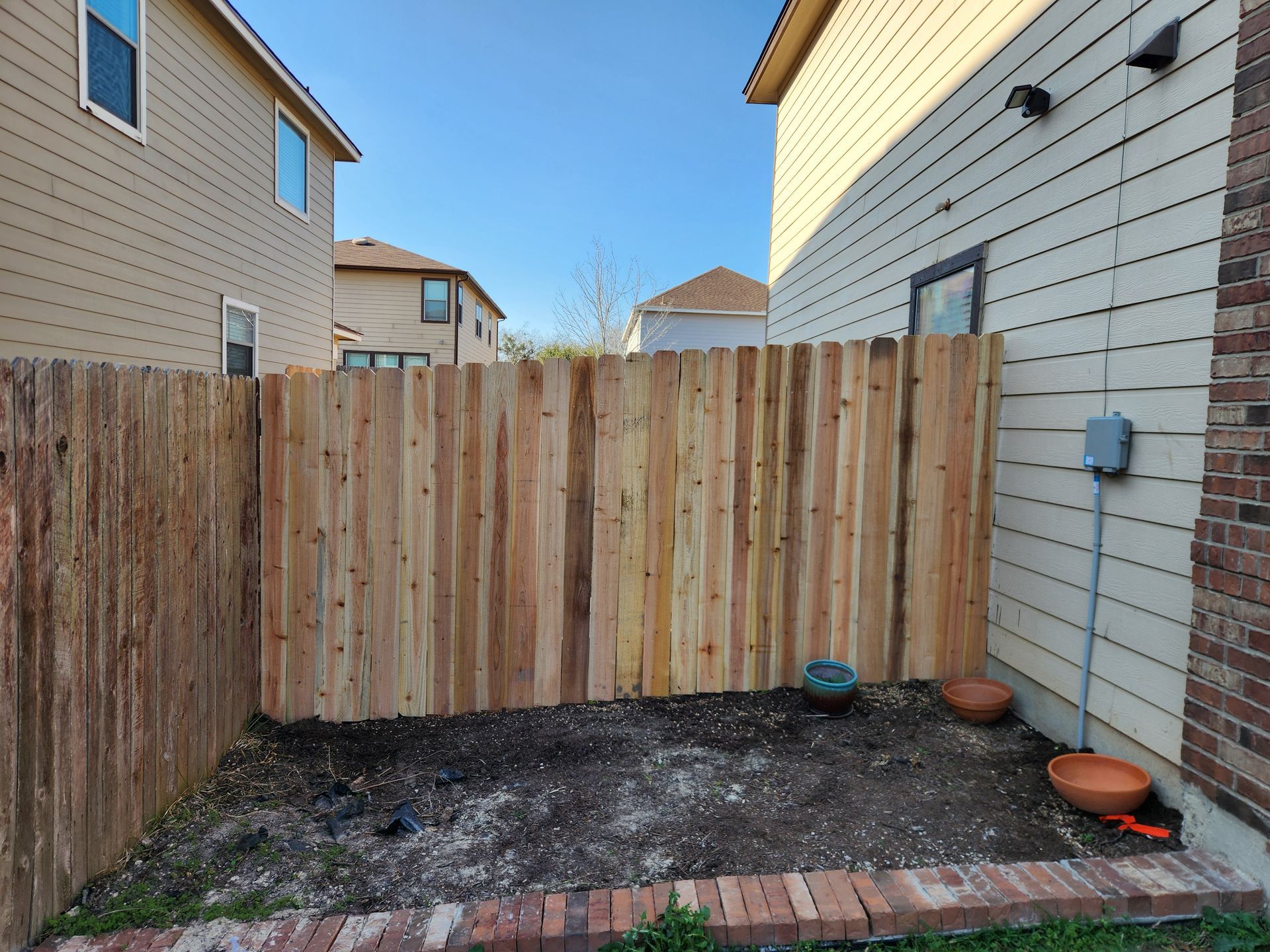 A wooden fence is in the backyard of a house.