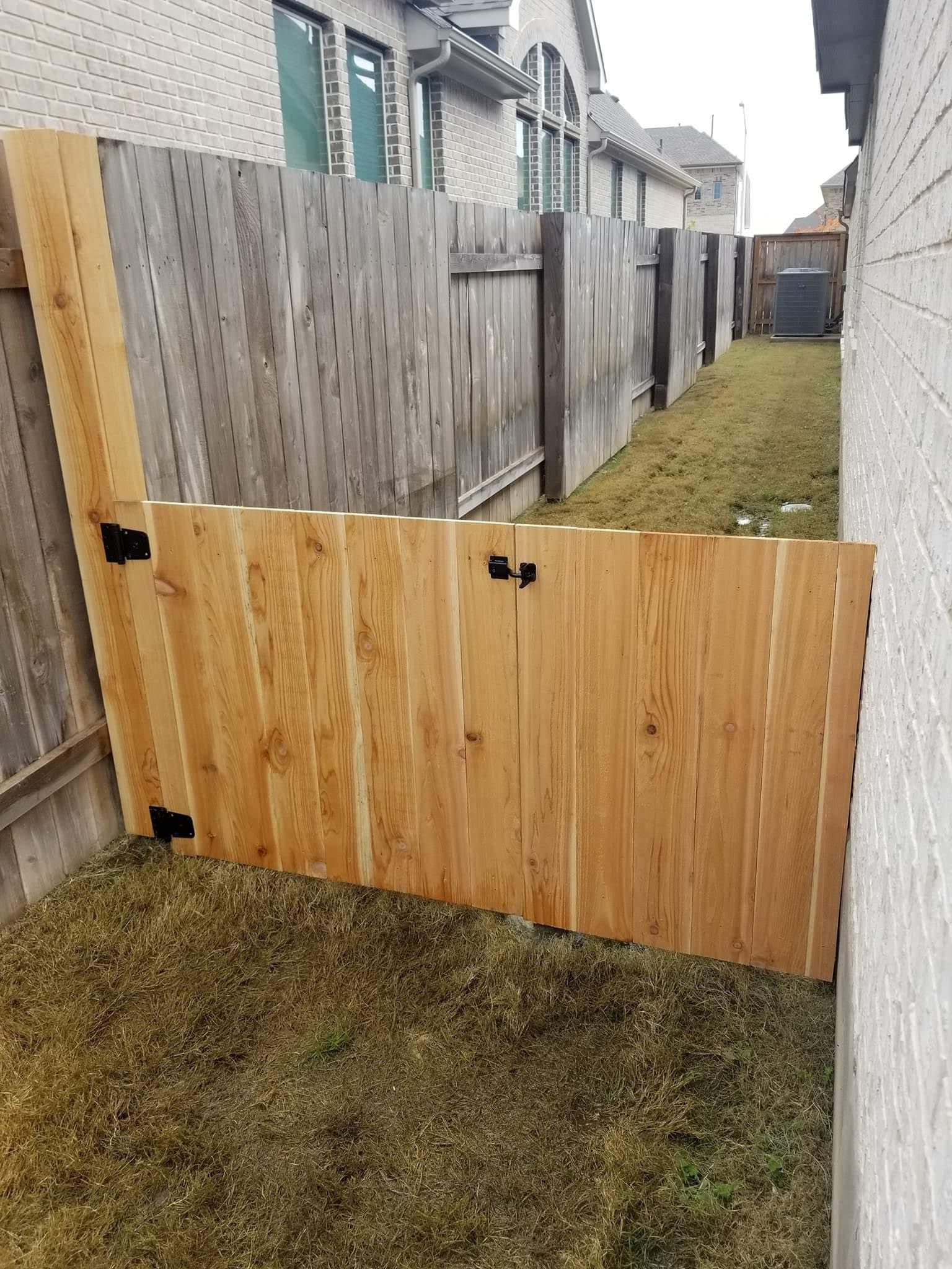 A wooden fence is sitting in the grass next to a building.