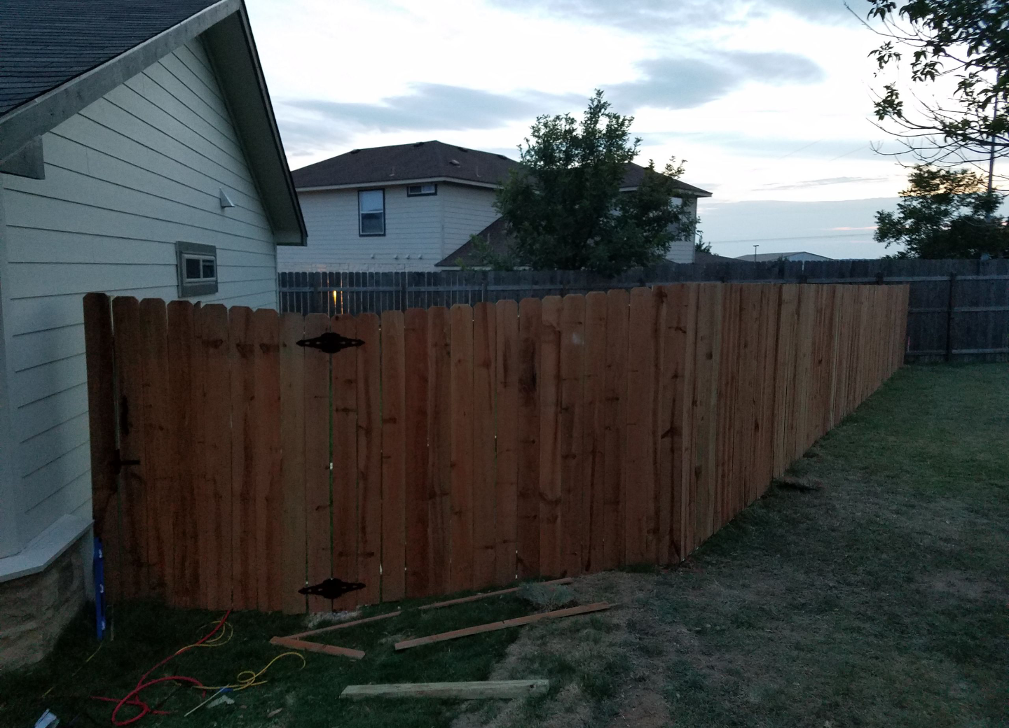 A wooden fence is being built in the backyard of a house