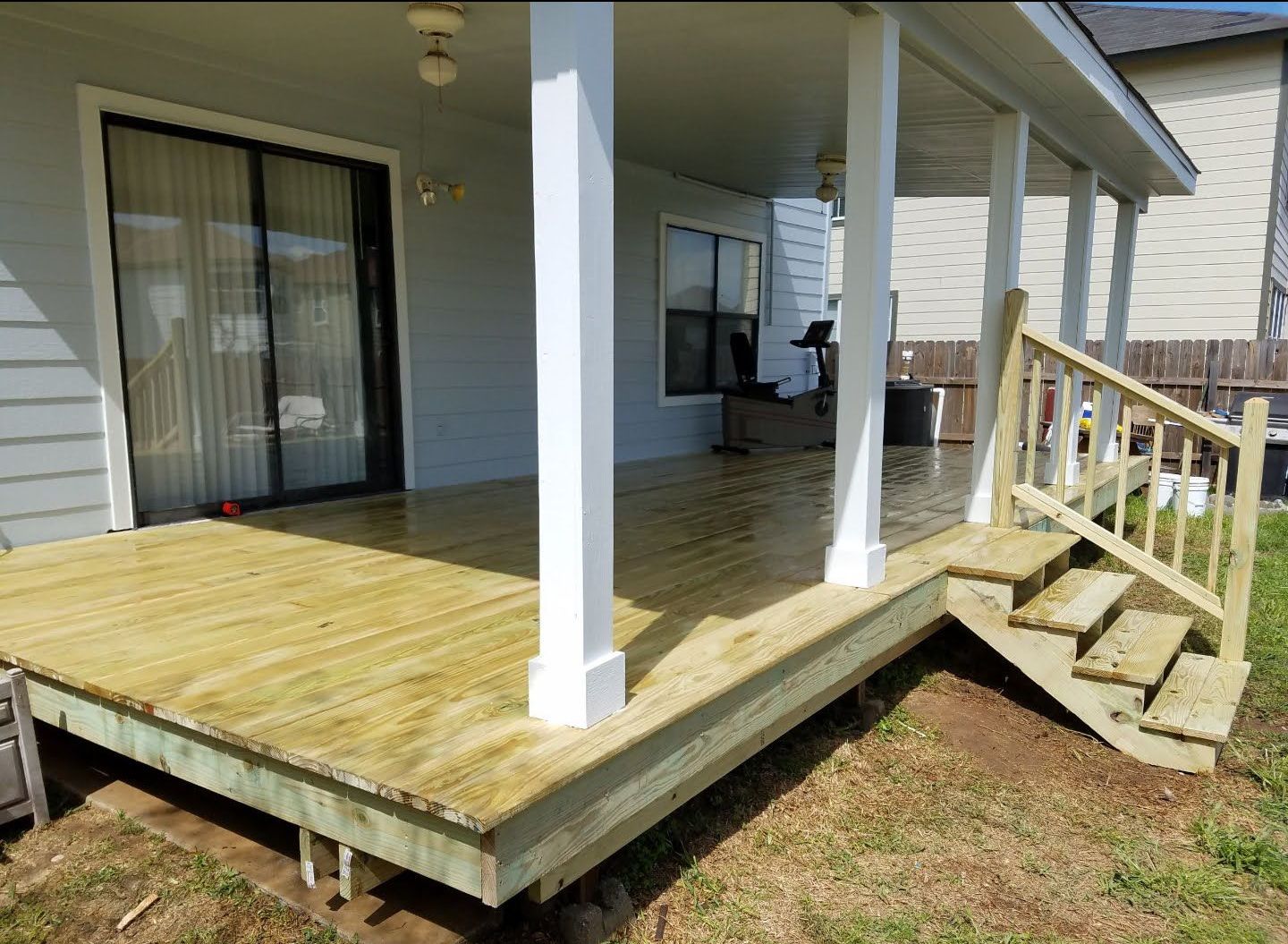 A wooden deck with stairs leading up to it is in front of a house.