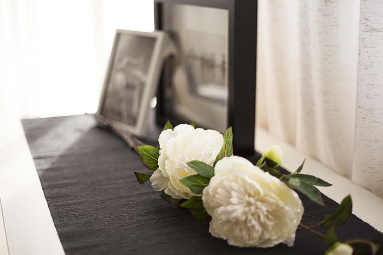 Two white flowers are sitting on a table next to a picture frame.