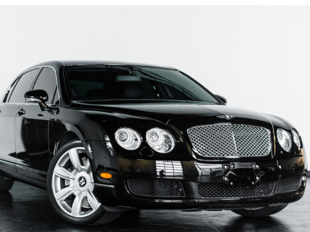 A black bentley is parked in front of a white background