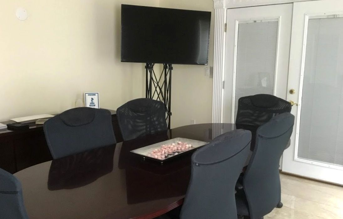 A conference room with a long table and chairs and a flat screen tv.