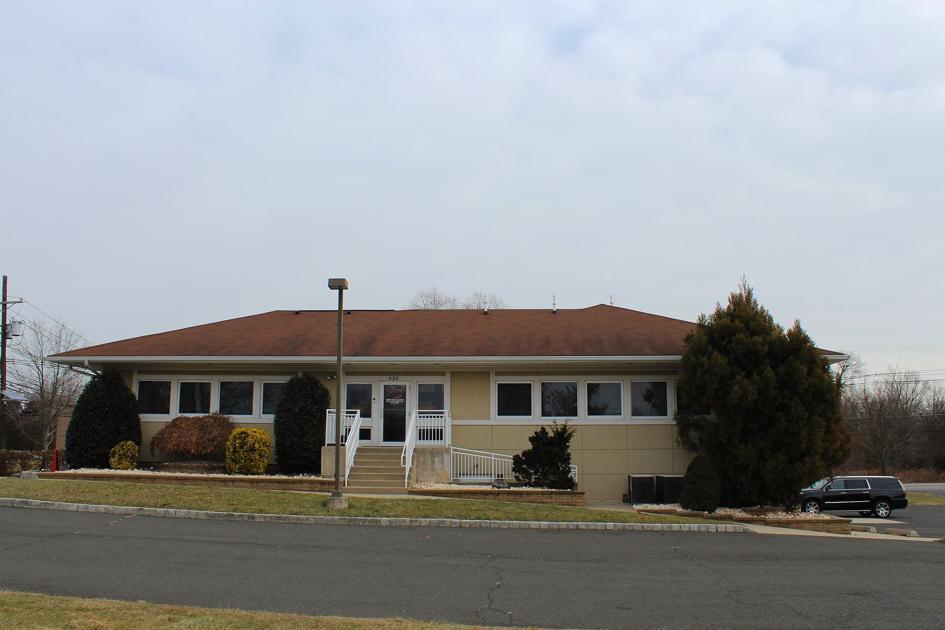 A house with a brown roof sits on the side of the road