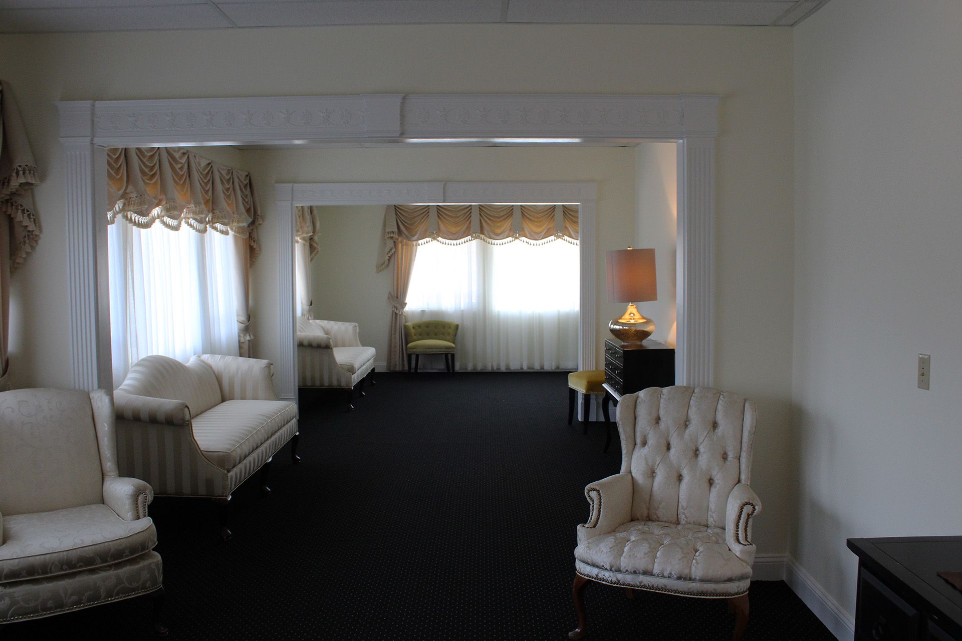 A living room with white furniture and black carpet
