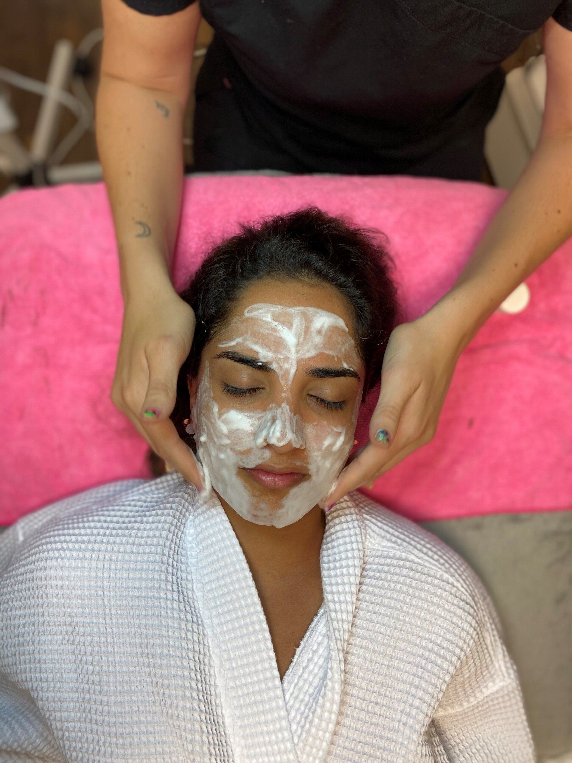 A woman with a white mask on her face is getting a massage