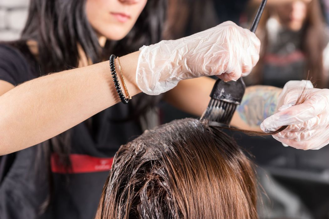 A woman is getting her hair dyed by a hairdresser in a salon.