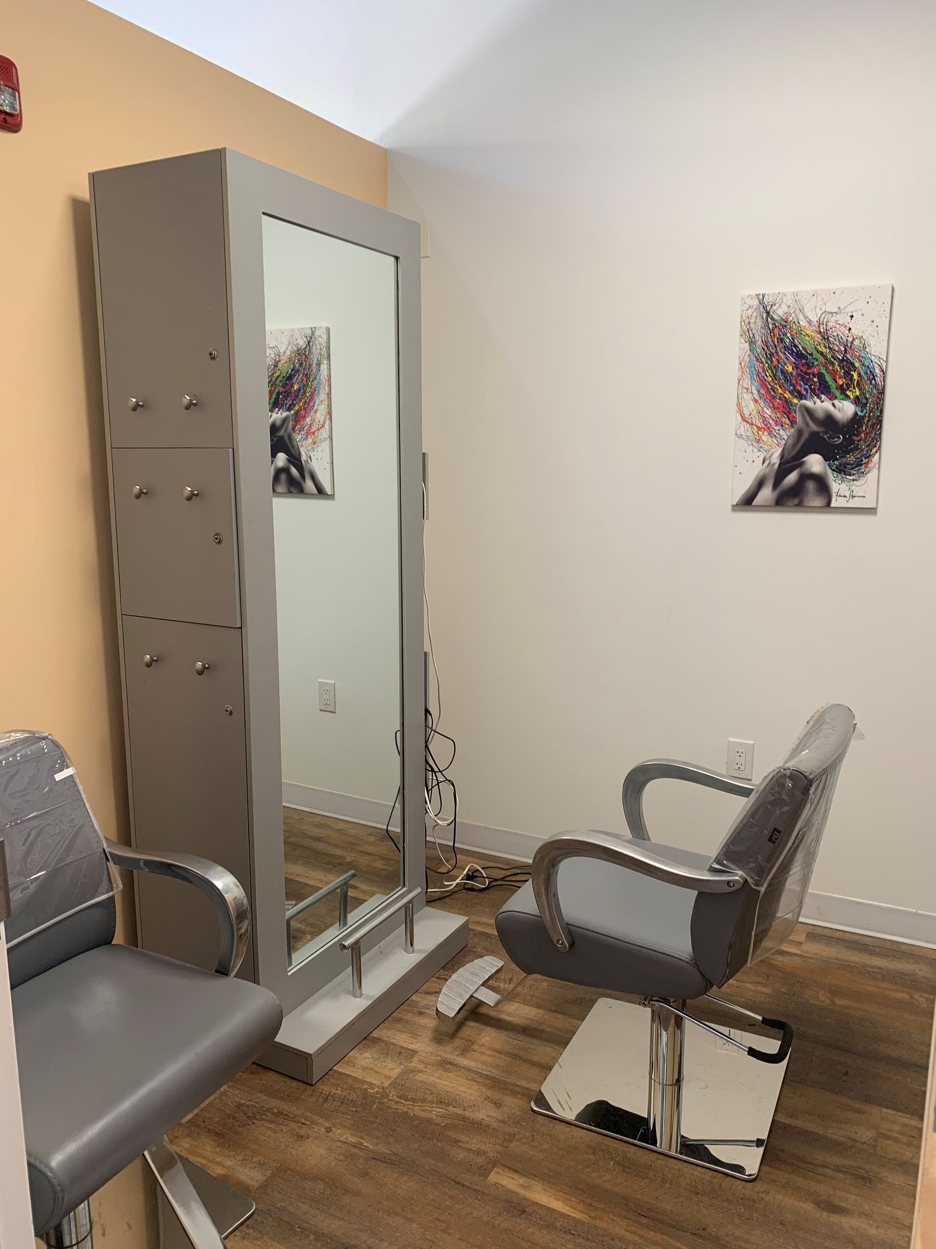 A hair salon with a chair , mirror and painting on the wall.